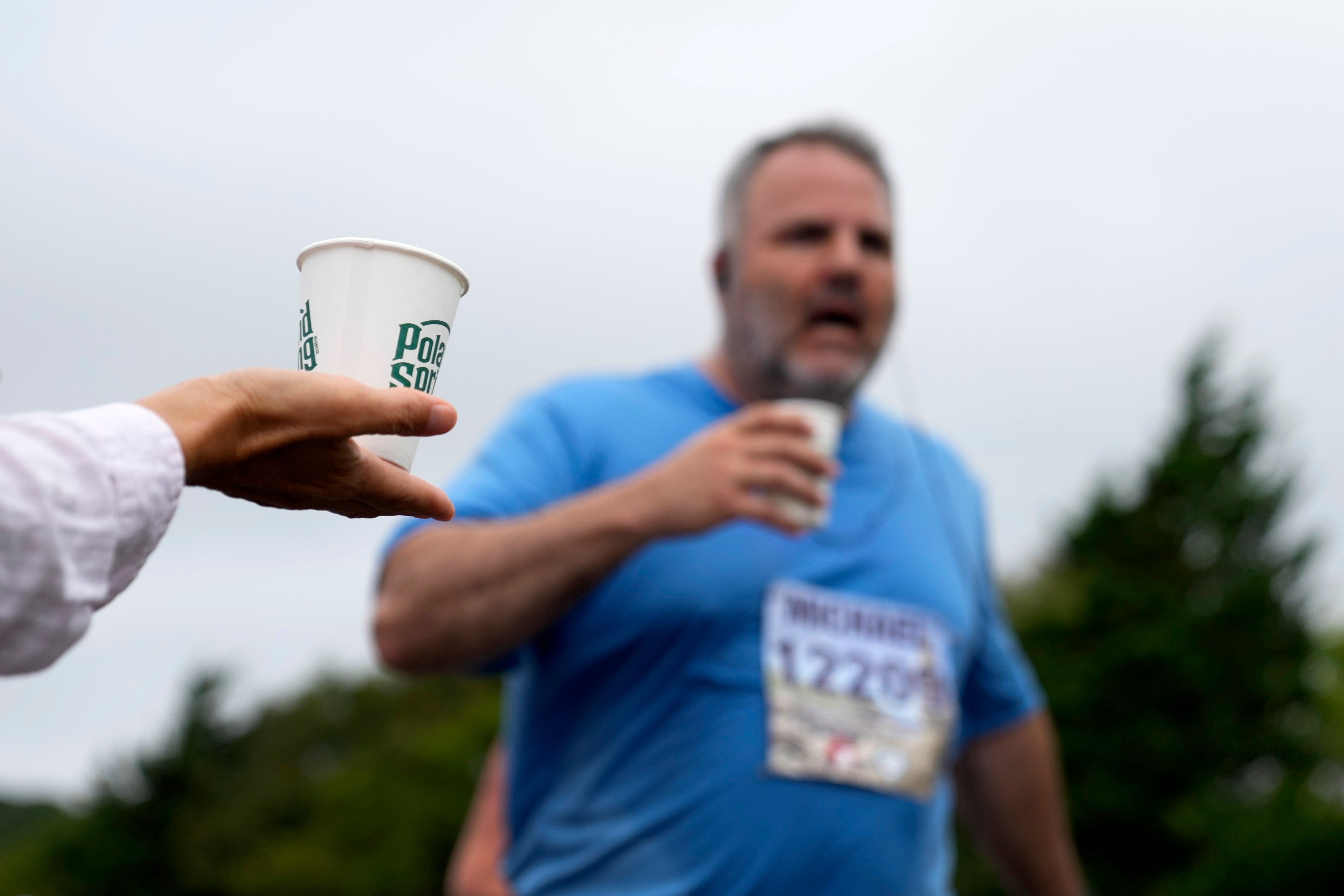 A volunteer holds out a cup of water for runners in the Falmouth Road Race in the US state of Massachusetts. Heatstroke among runners is becoming more of a risk as climate change increases the number of hot days. Photo: AP  