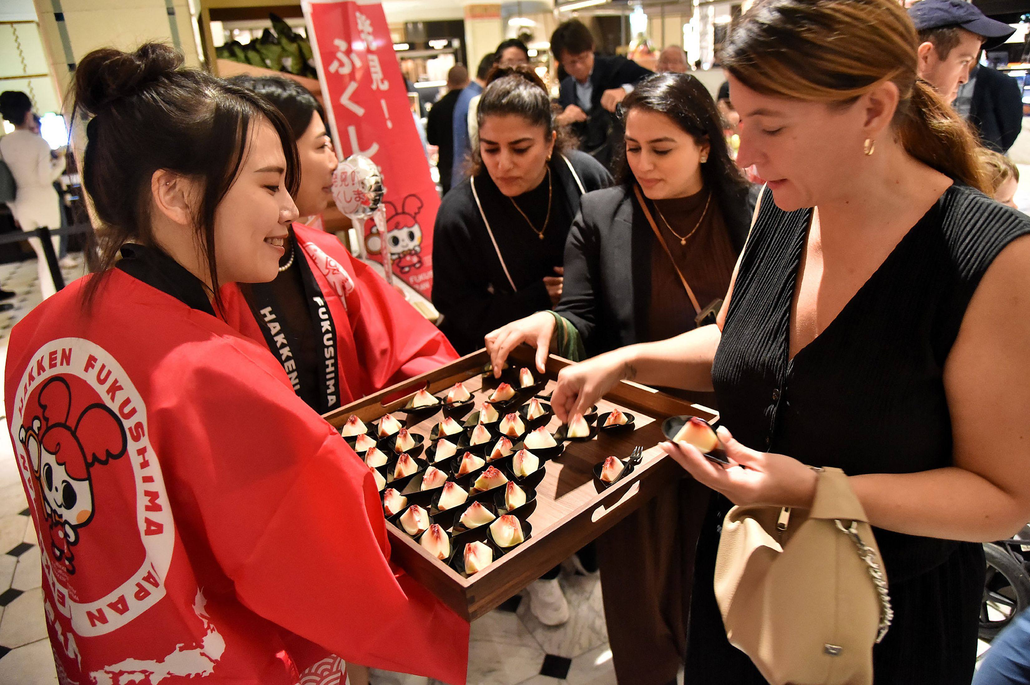 A customer tries peaches from Japan’s Fukushima prefecture, which went on sale at luxury department store Harrods in central London on September 7. Photo: AFP