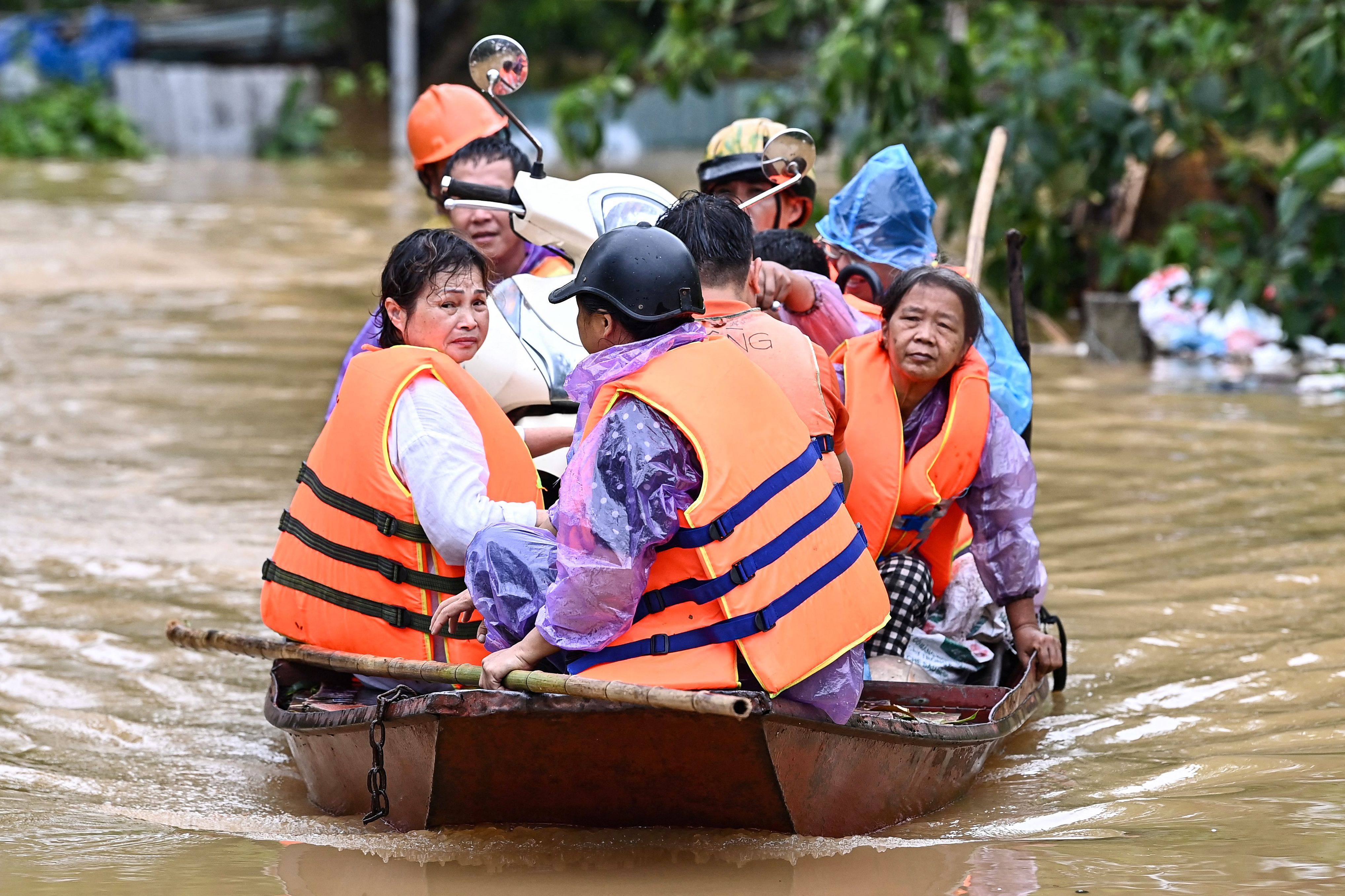 Local residents are evacuated on a boat through a flooded street in Hanoi on September 10. Photo: AFP