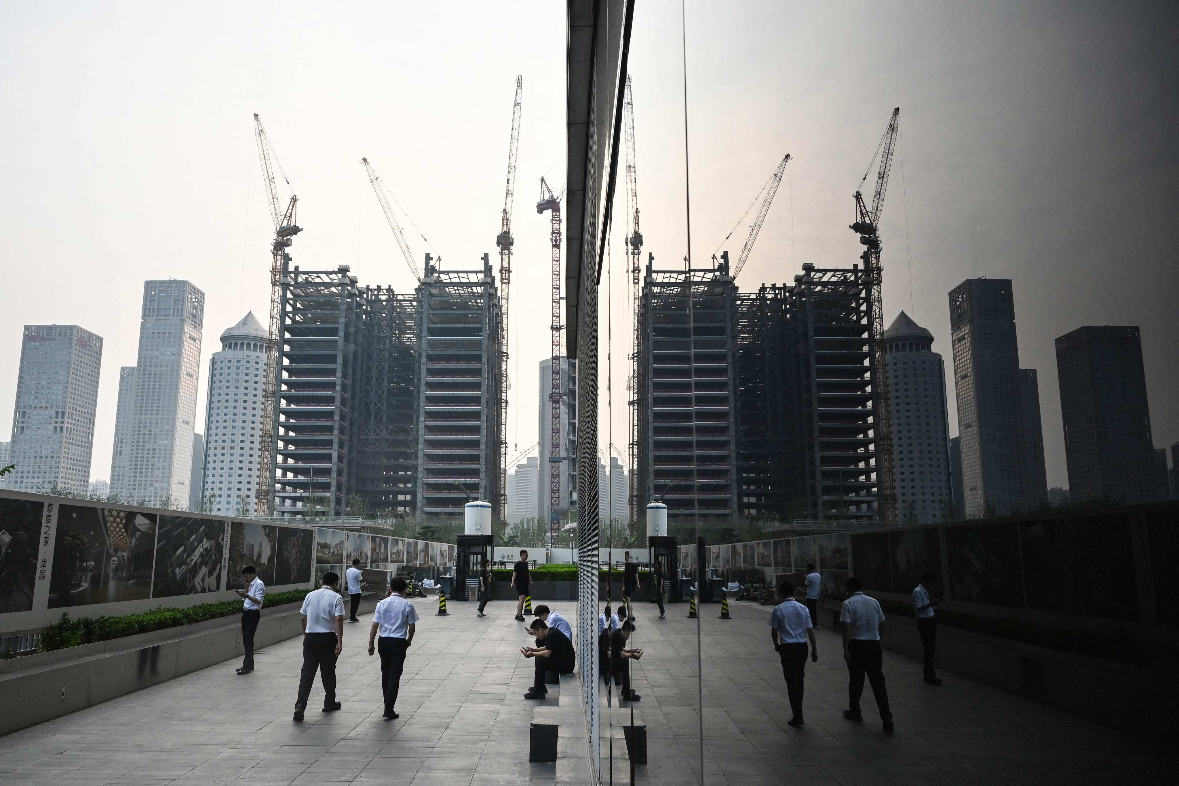 Office workers walk beside the wall of a construction site in the central business district of Beijing. Photo: AFP