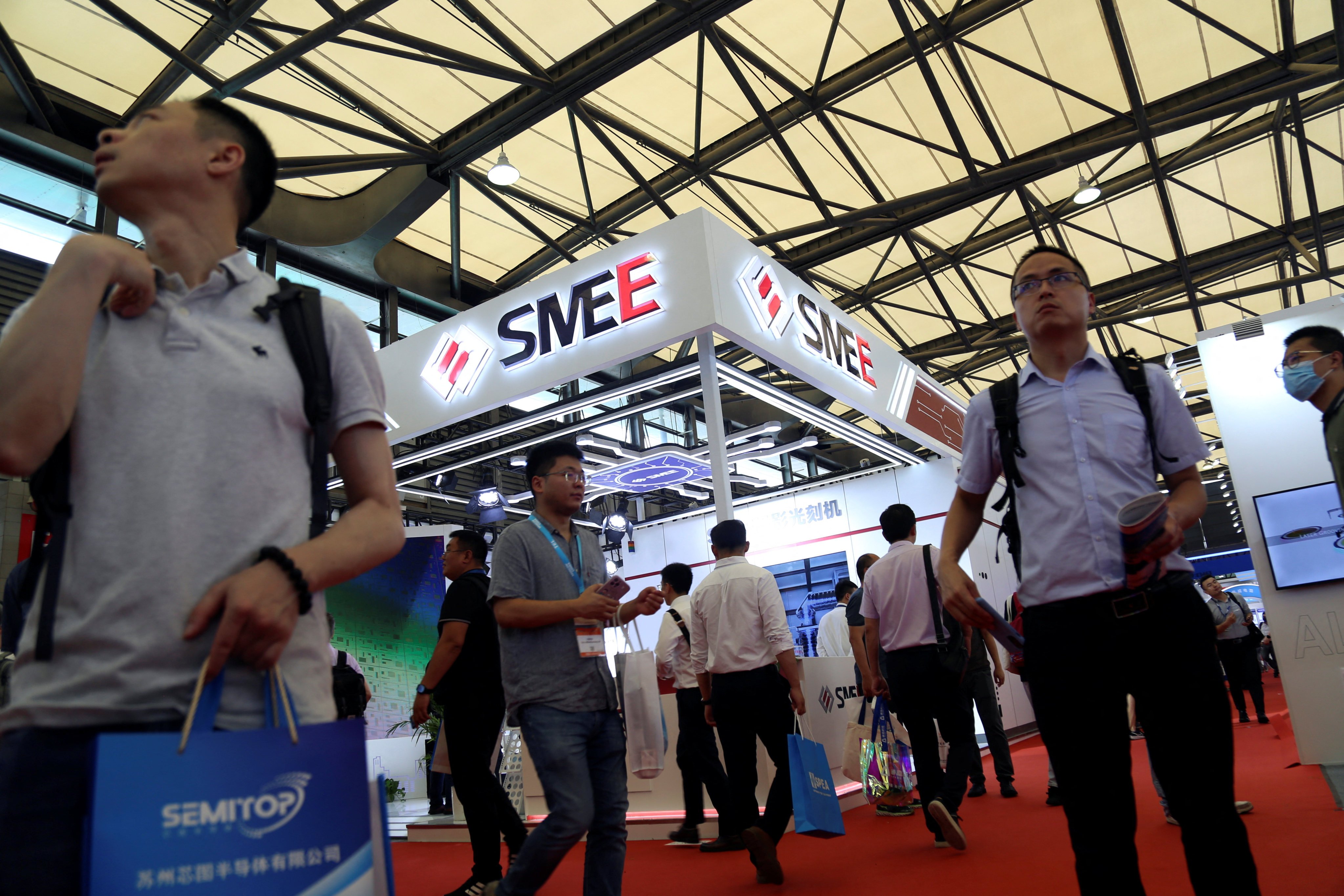 Visitors walk past the Shanghai Micro Electronics Equipment (SMEE) booth during Semicon China, a trade fair for the semiconductor industry, on June 29, 2023. Photo: Reuters