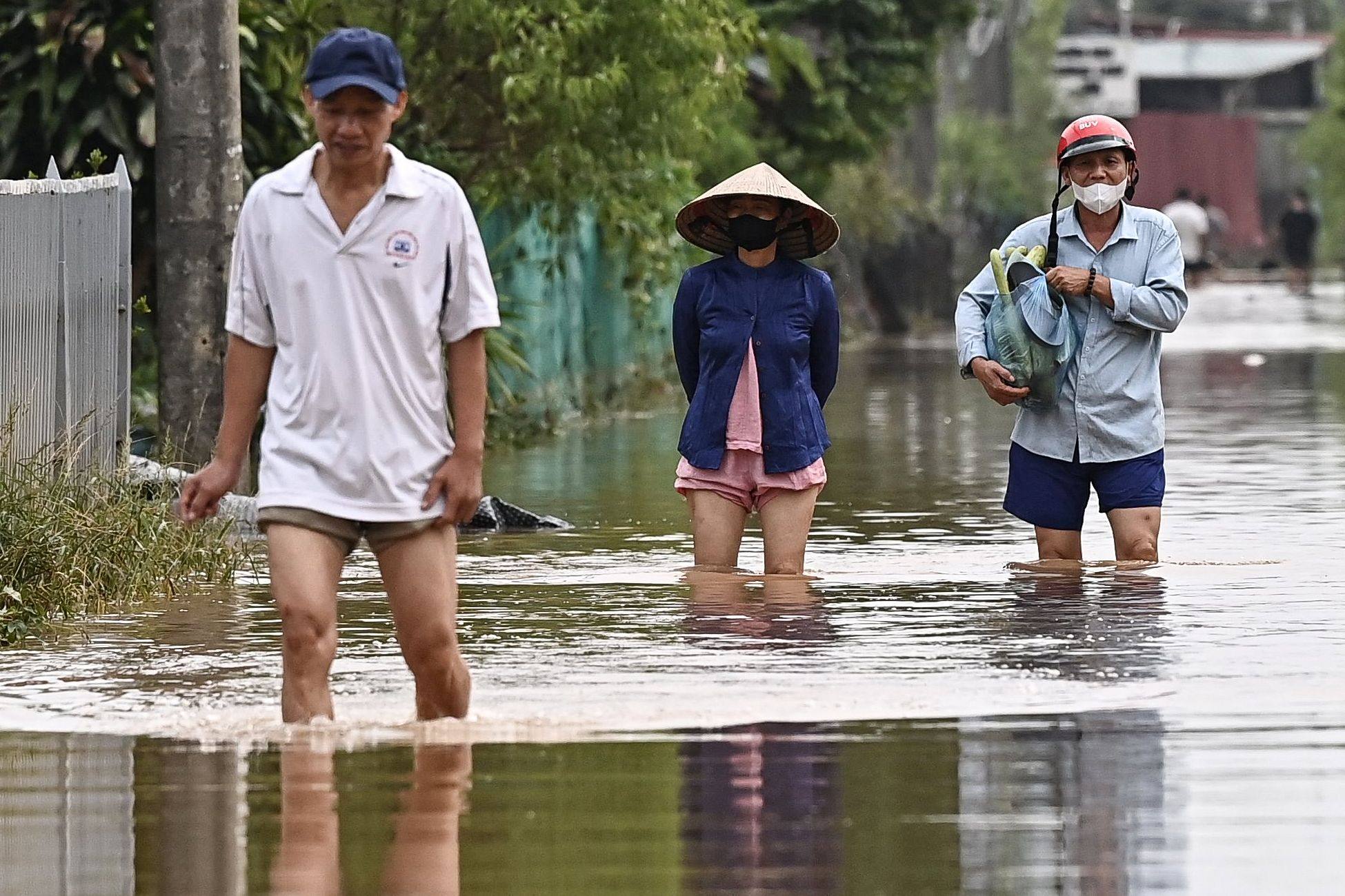 People wade through flood waters in Hanoi. Photo: AFP