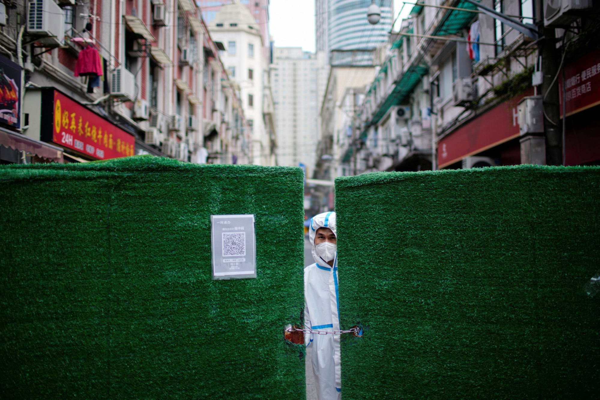 A worker in a protective suit peers through a gap in barriers at a closed residential area in Shanghai during lockdown measures in China in May 2022. Photo: Reuters