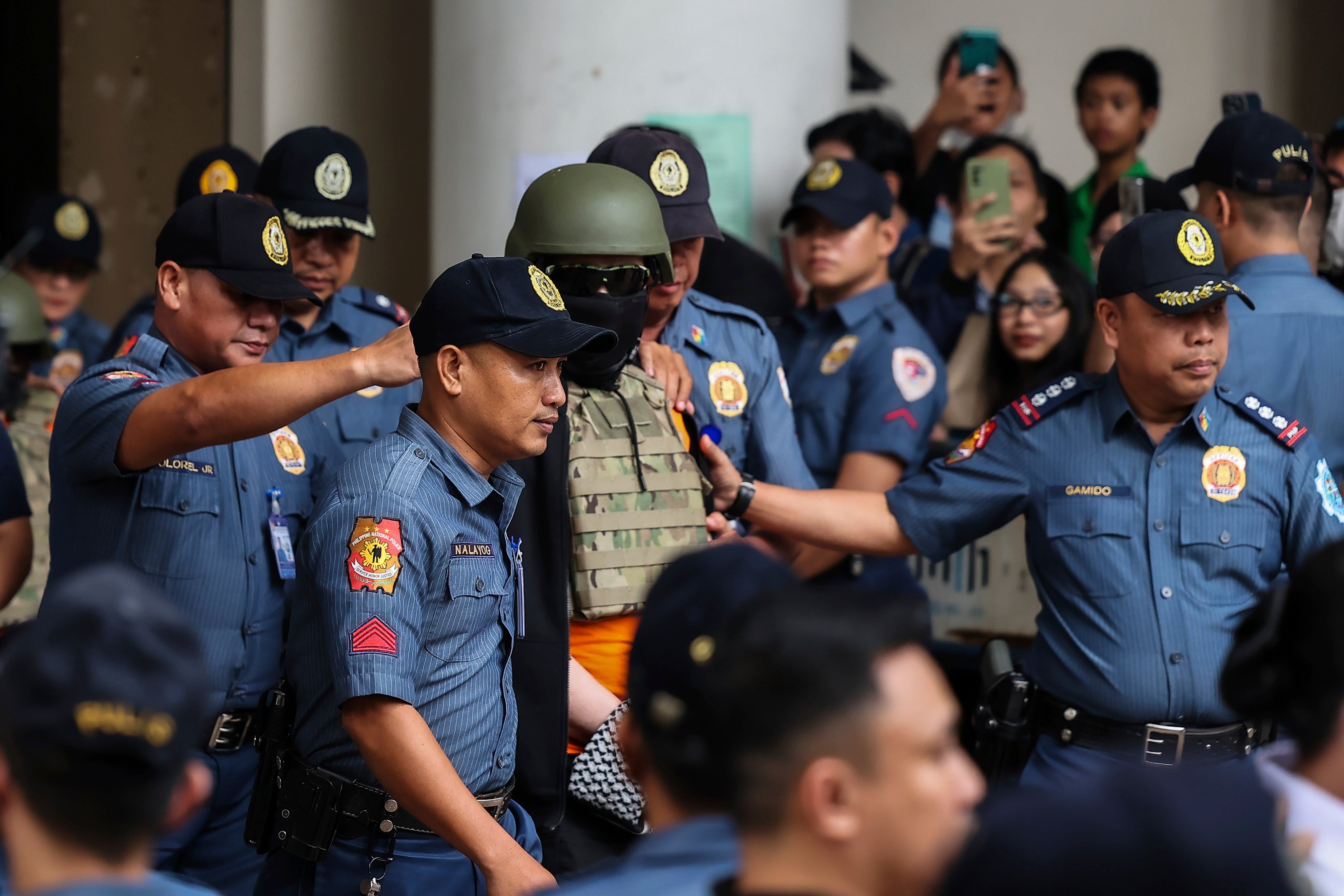 Apollo Quiboloy (middle, in a helmet and flak jacket) leaves the Pasig Regional Trial Court. He pleaded not guilty on Friday to several criminal charges including sexually abusing a child. Photo: AP