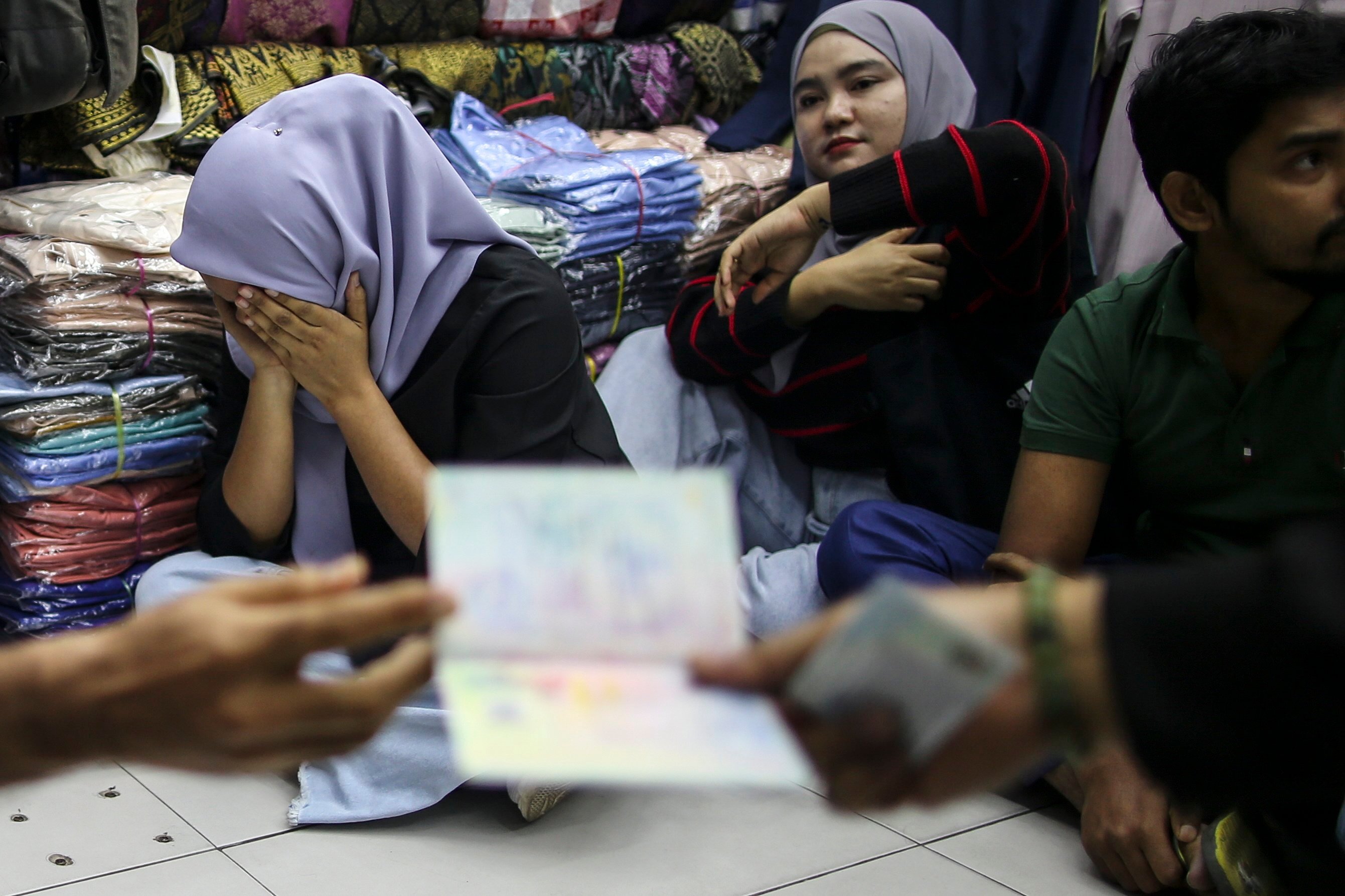 Detainees react during an immigration raid at a clothing store Malaysia on August 15. Photo: EPA-EFE