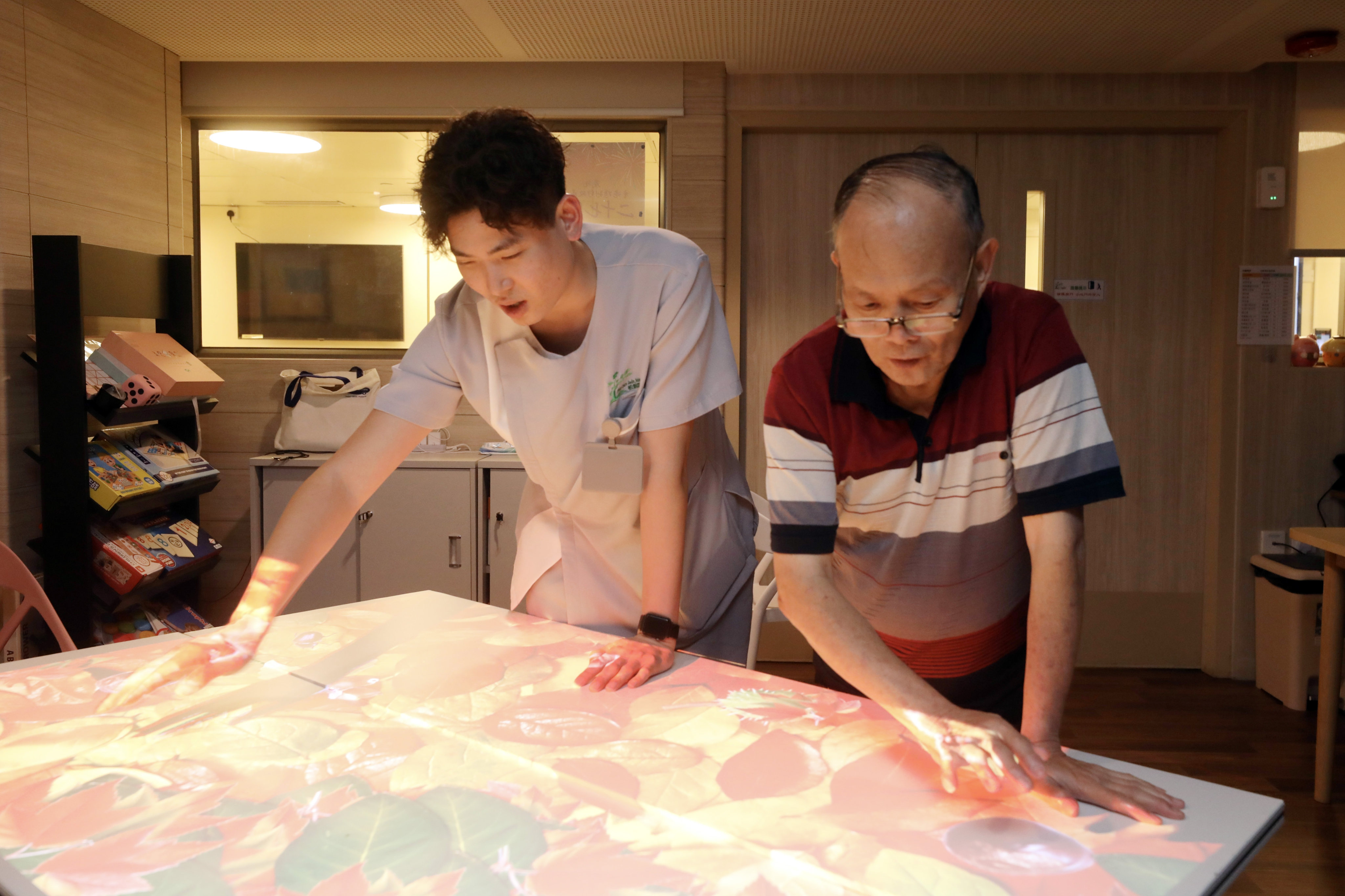 Kaden Yau (left) plays a game with a resident of Pine Care Jade Maison, an elderly care home in Sheung Shui. Photo: Sun Yeung
