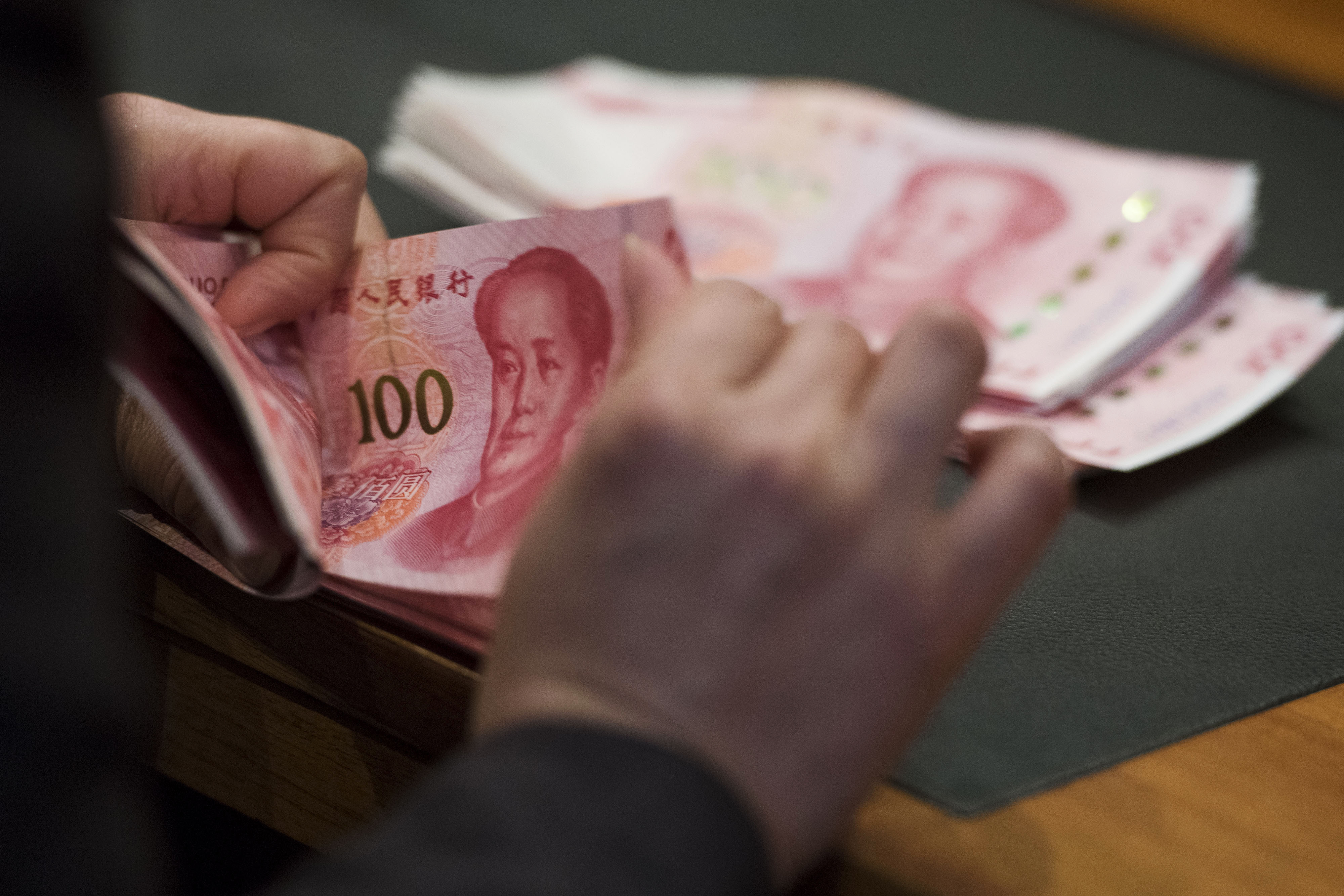 An employee counts Chinese yuan banknotes in an arranged photograph at the Bank of China Hong Kong headquarters, on November 12, 2015. Photo: Bloomberg