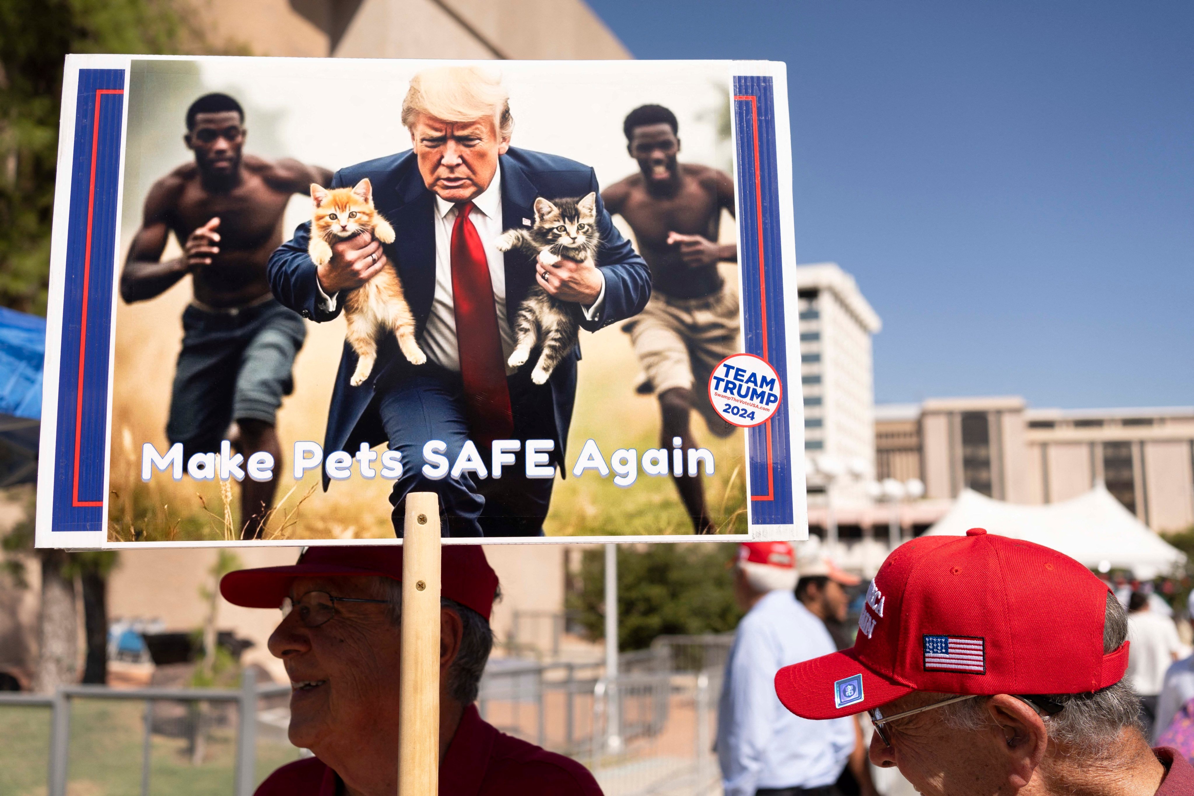 A man carries an AI-generated image of former US president Donald Trump carrying cats away from Haitian immigrants, a reference to falsehoods spread about Springfield, Ohio, during a campaign rally in Tucson, Arizona, on Thursday. Photo: TNS