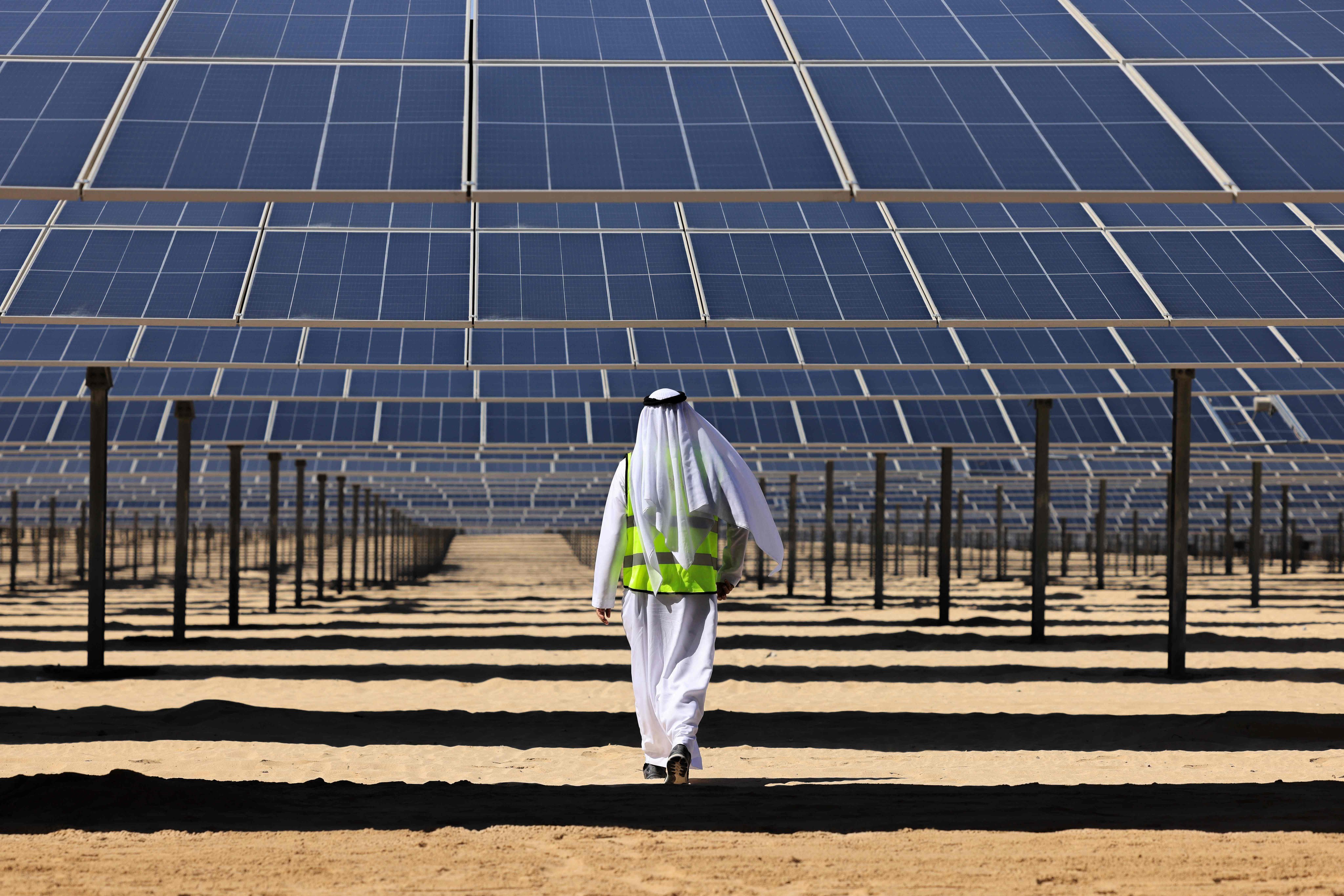 An Emirati man walks beneath photovoltaic panels at al-Dhafra solar power project south of Abu Dhabi in November 2023. Photo: AFP