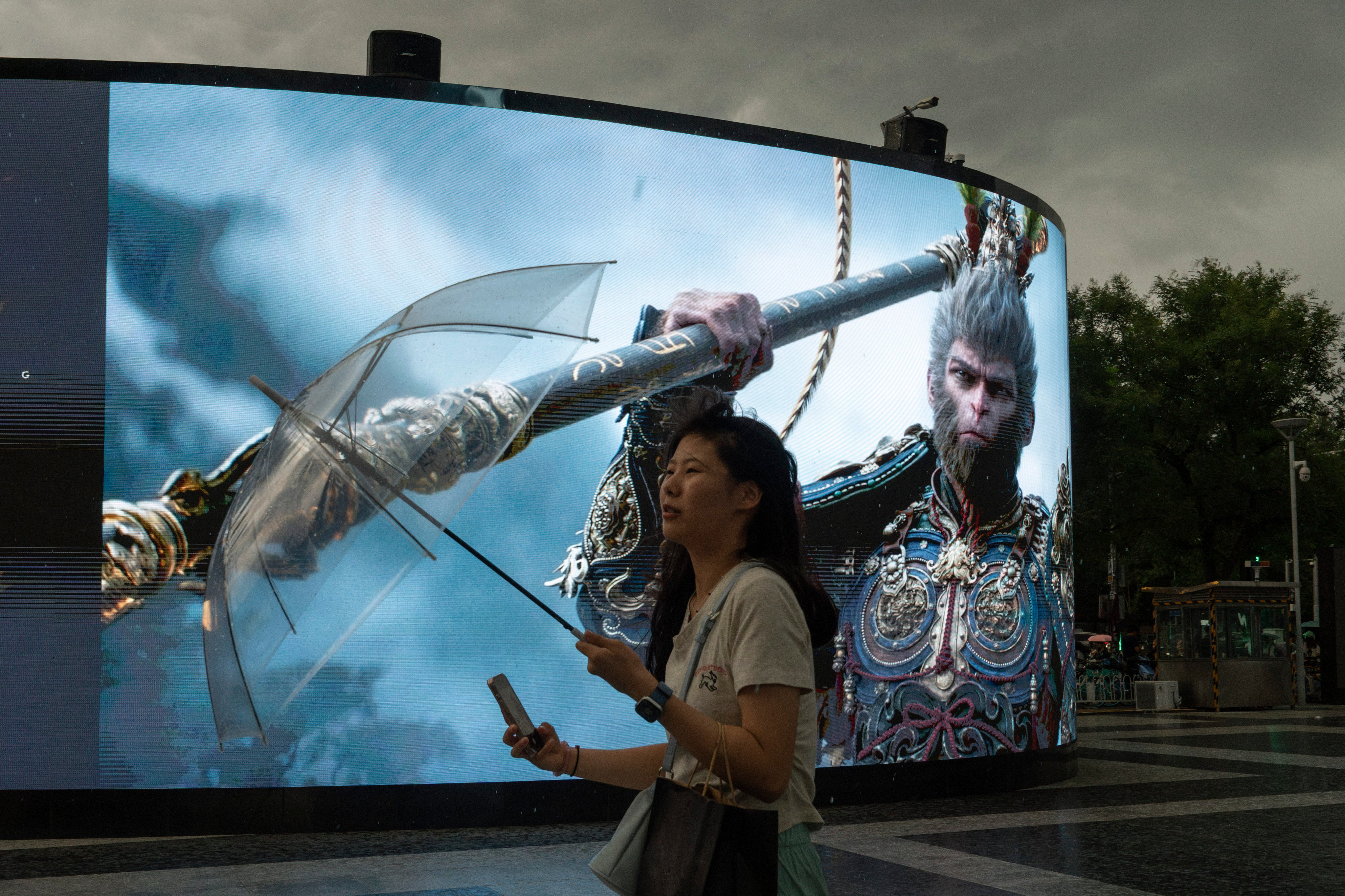 A woman holds up an umbrella as it rains near an advertisement promoting blockbuster Chinese video game Black Myth: Wukong in Beijing. Photo: AP