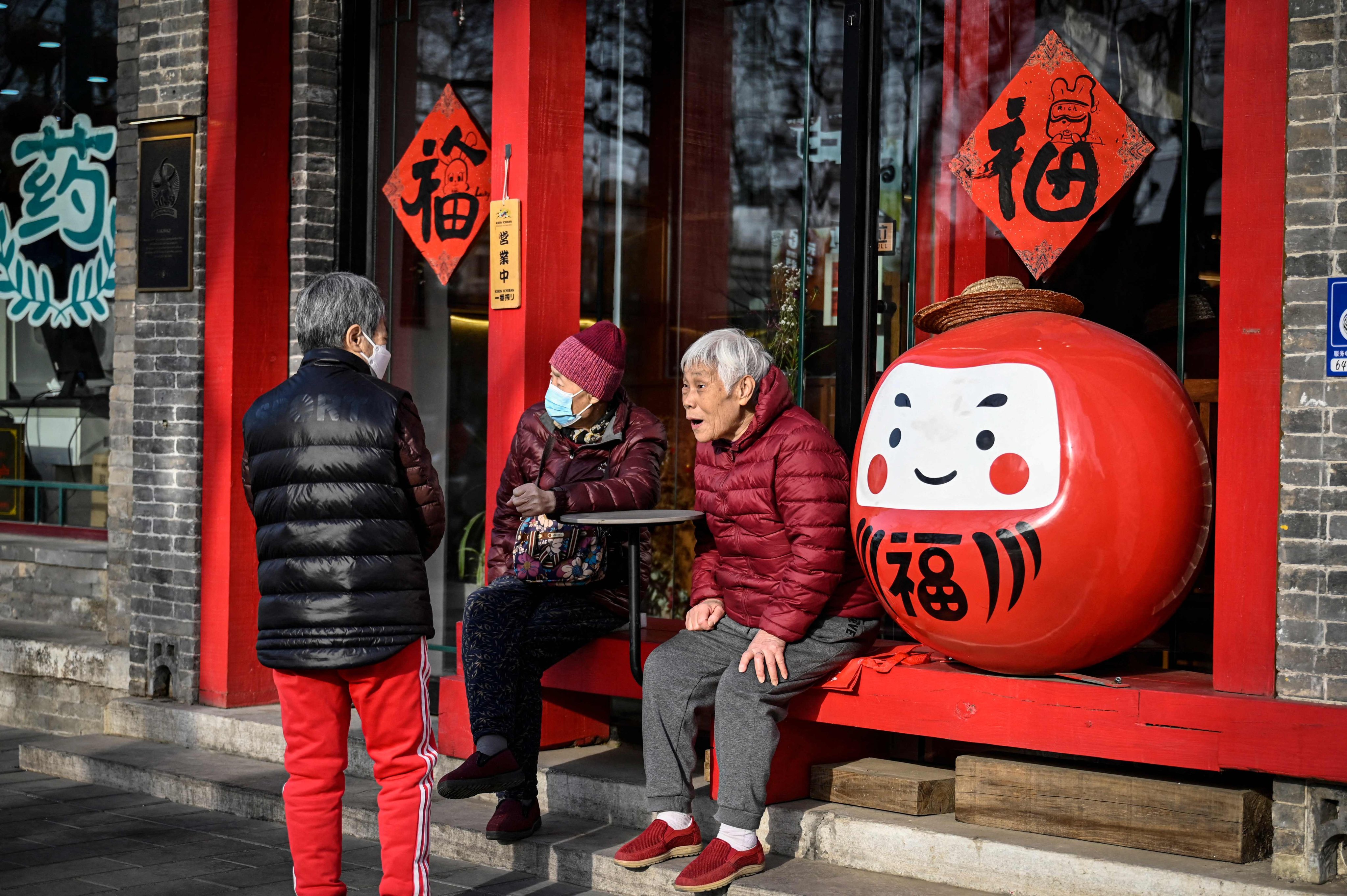 Elderly people chat outside a restaurant along a street in Beijing. Photo: AFP