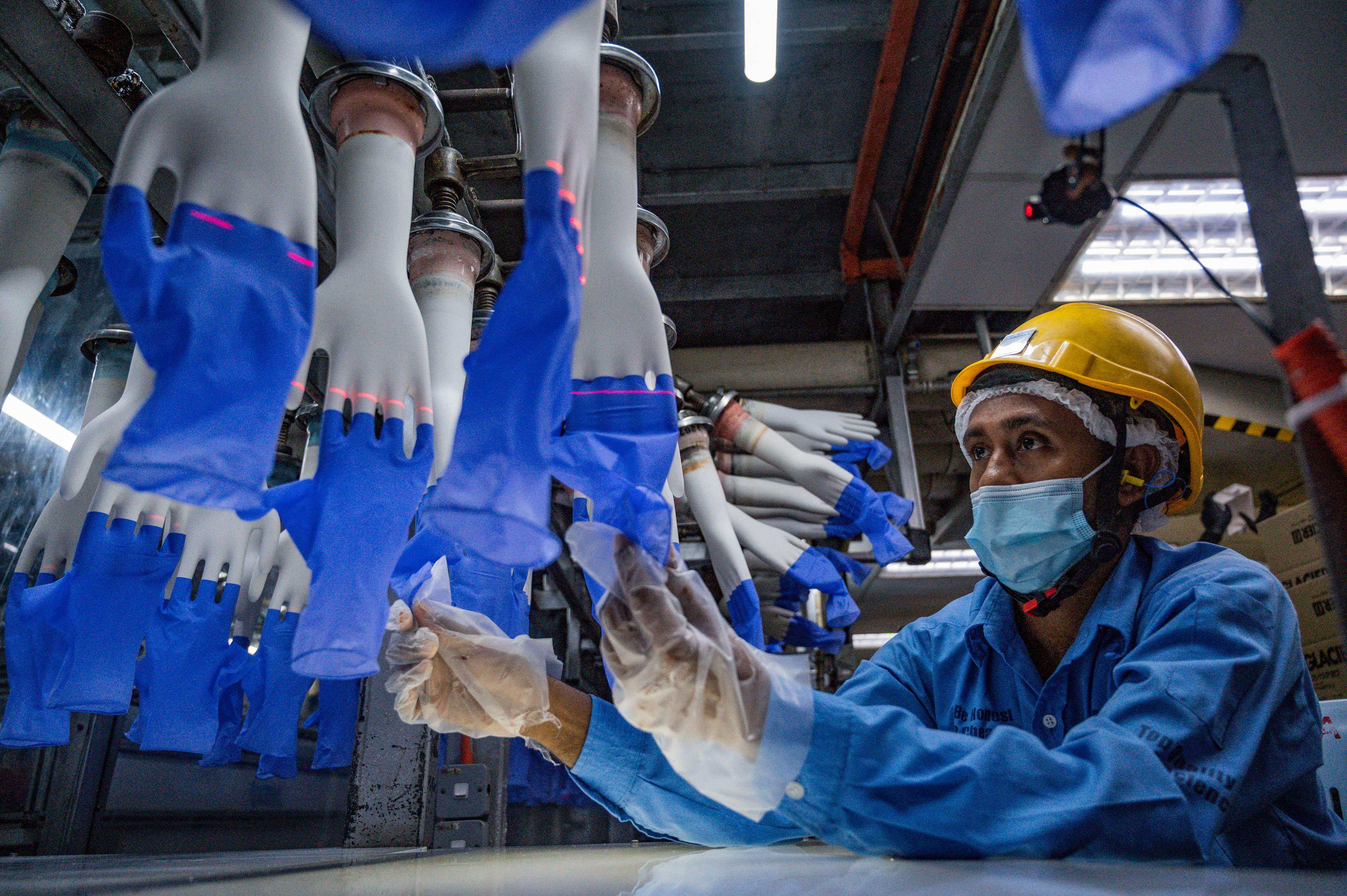 A worker inspects disposable gloves at the Top Glove factory on the outskirts of Kuala Lumpur in August 2020. Photo: AFP