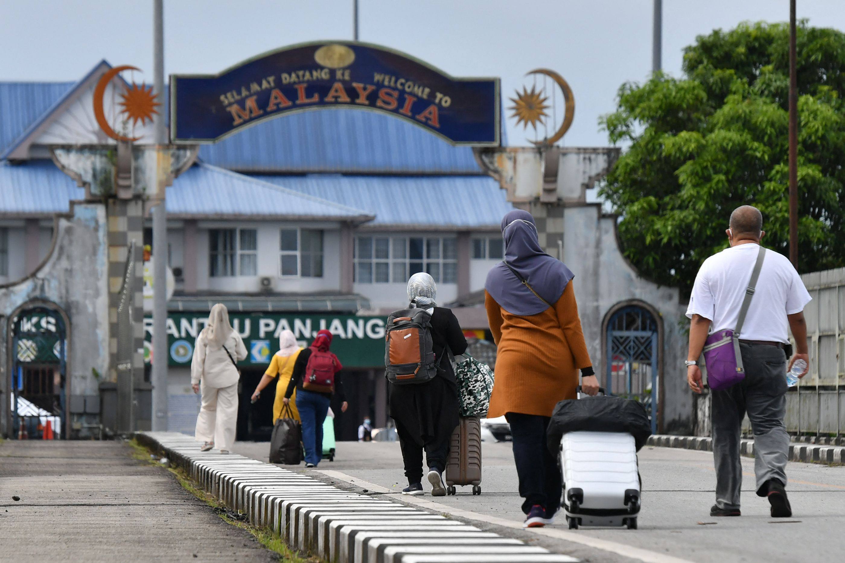 People walk towards Malaysia from the Sungai Kolok district in southern Thailand’s Narathiwat province. Photo: AFP