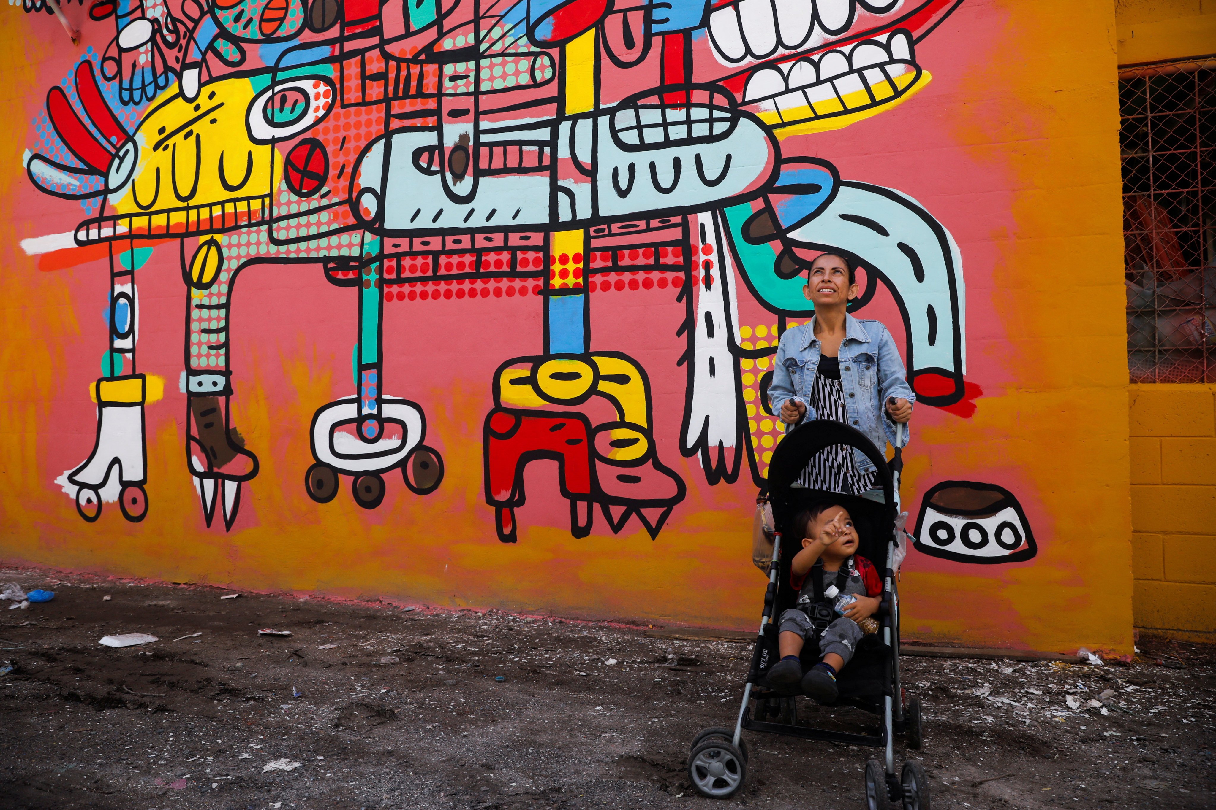 A woman and a child by a mural in Zacamil, San Salvador. Photo: Reuters