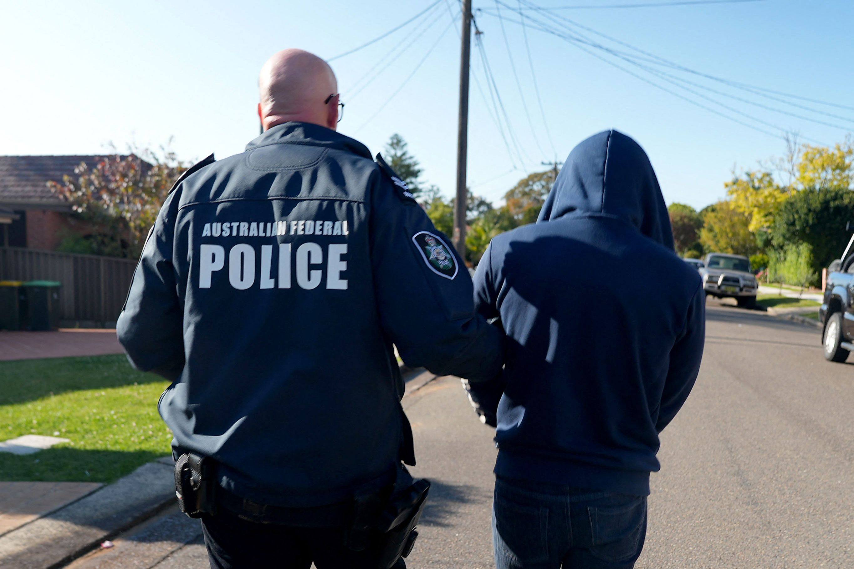 An Australian federal police officer arrests a suspect allegedly involved in Ghost, an encrypted messaging app used by criminals worldwide to facilitate drug deals and order killings, at an unknown location. Photo: AFP/Australia federal police 