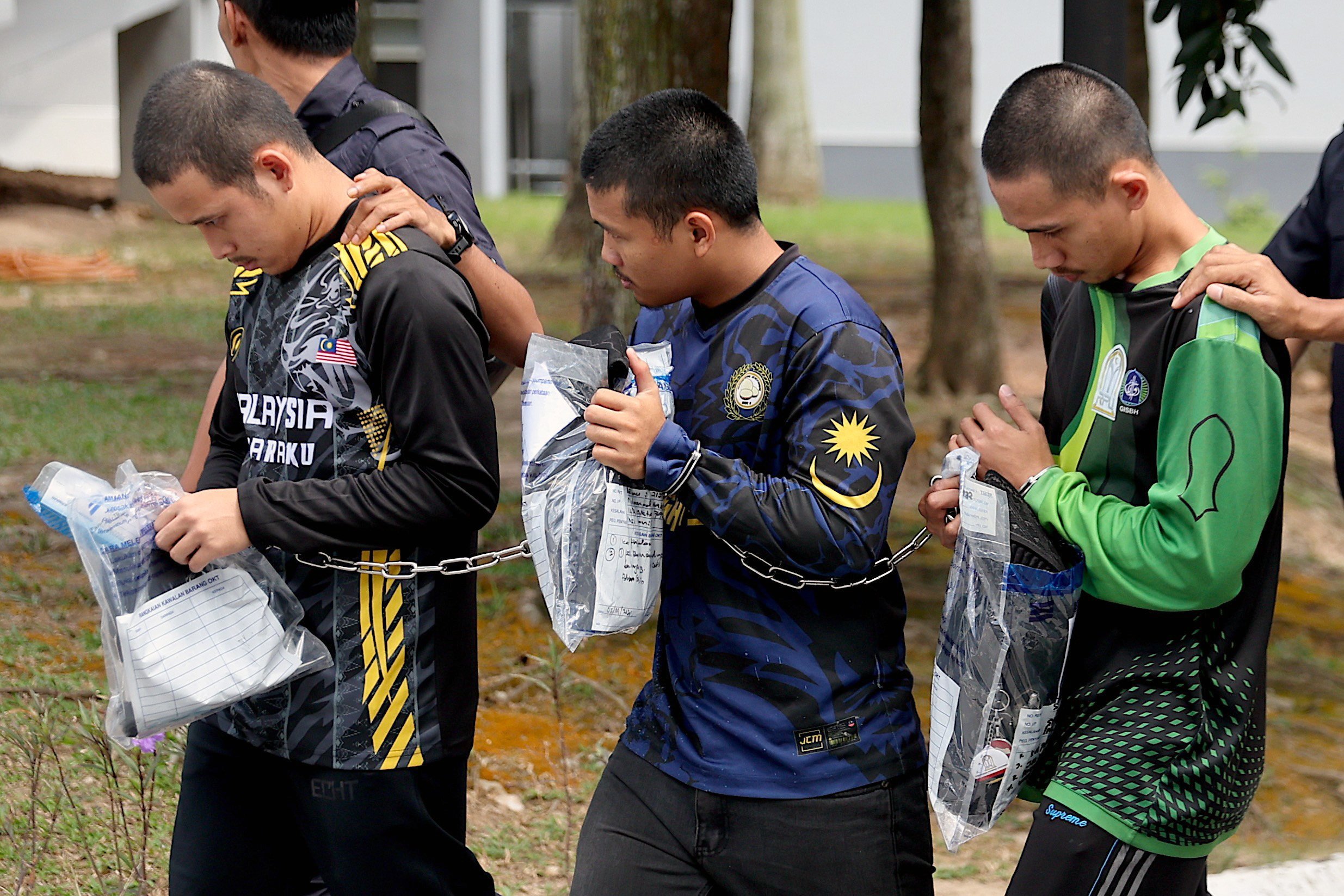 Three members of Global Ikhwan Services and Business Holdings (GISBH) escorted by Royal Malaysian Police officers depart after facing charges at a court in Seremban, Malaysia, on September 19. Photo: EPA-EFE