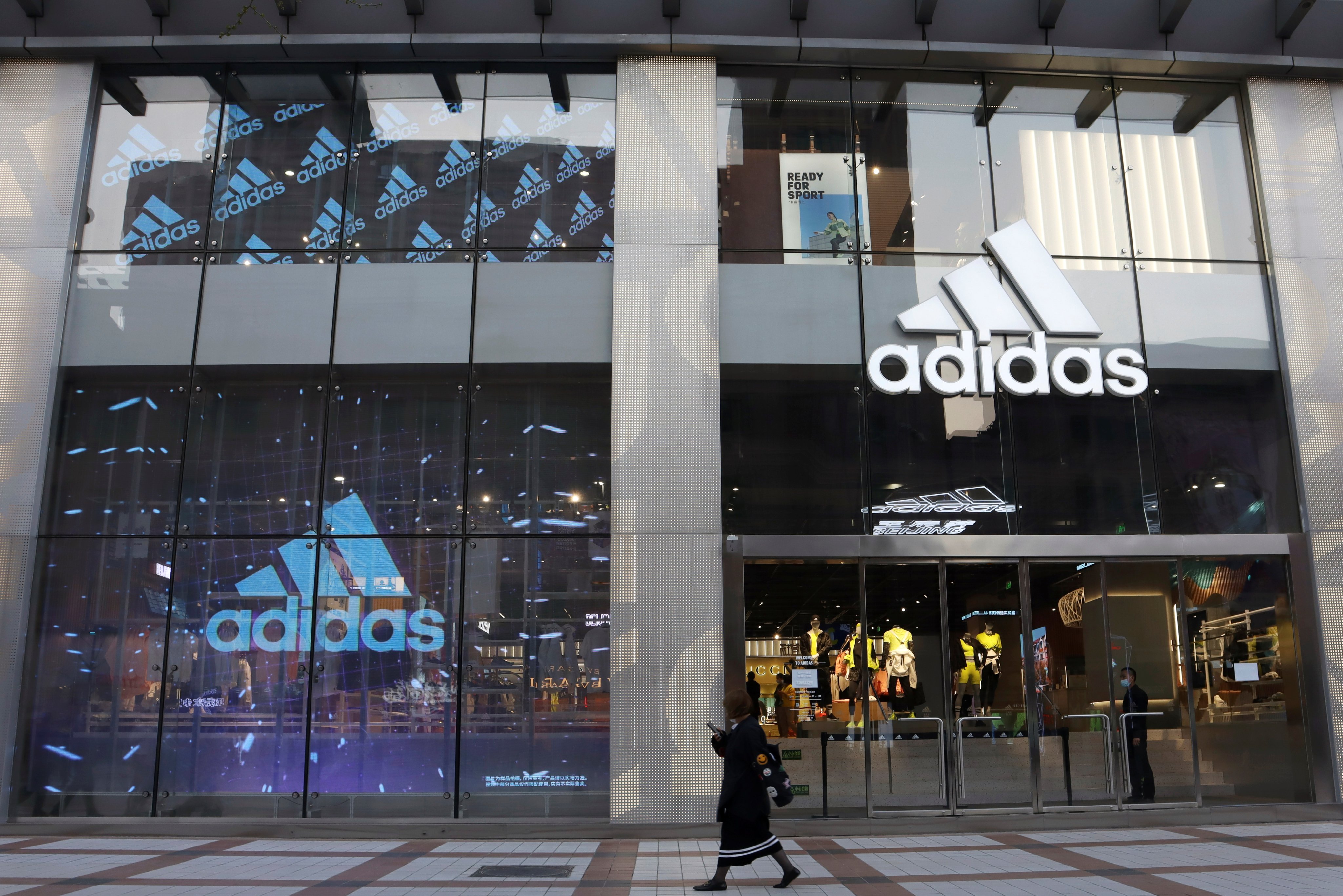 A woman walks past a store of sporting goods retailer Adidas at a shopping mall in Beijing on March 25, 2021. Photo: Reuters