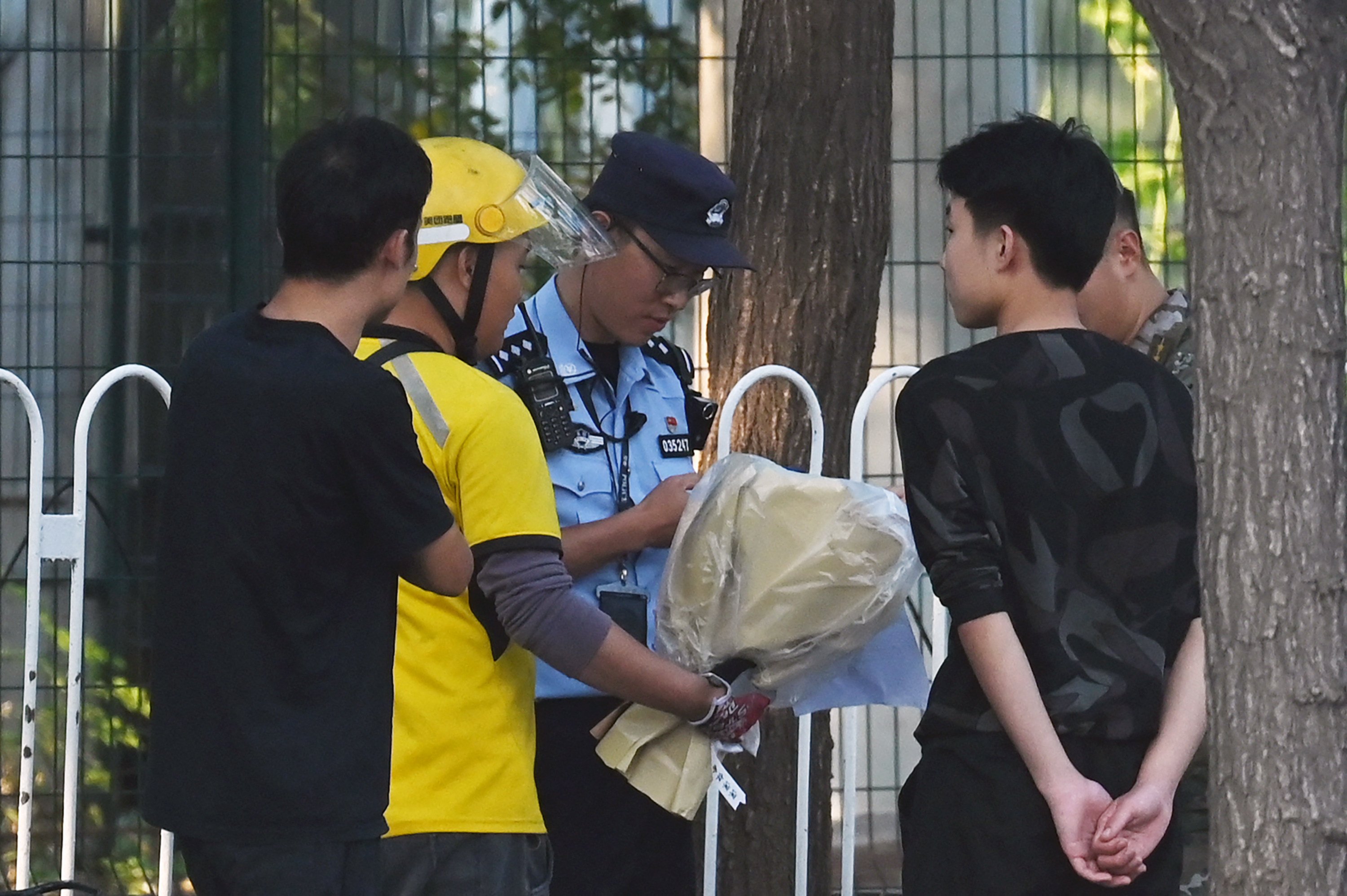 Police and security check a delivery rider (second from left) who arrived with what appeared to be a bouquet of flowers at the entrance of the Japanese embassy in Beijing on September 19. Photo: TNS