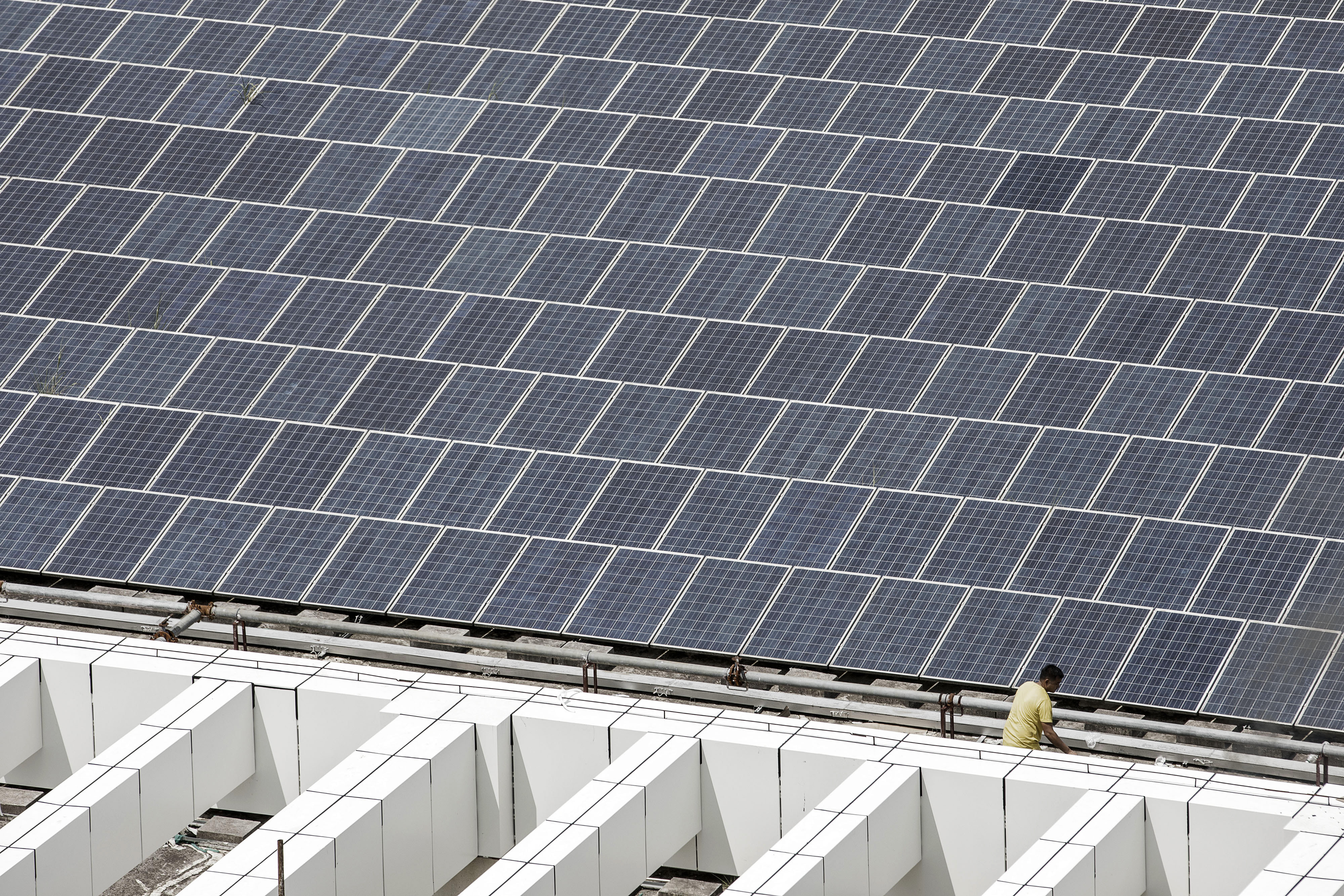 A worker walks past a rooftop solar farm at electric vehicle maker BYD’s headquarters in Shenzhen, China, in September 2017. Photographer: Bloomberg