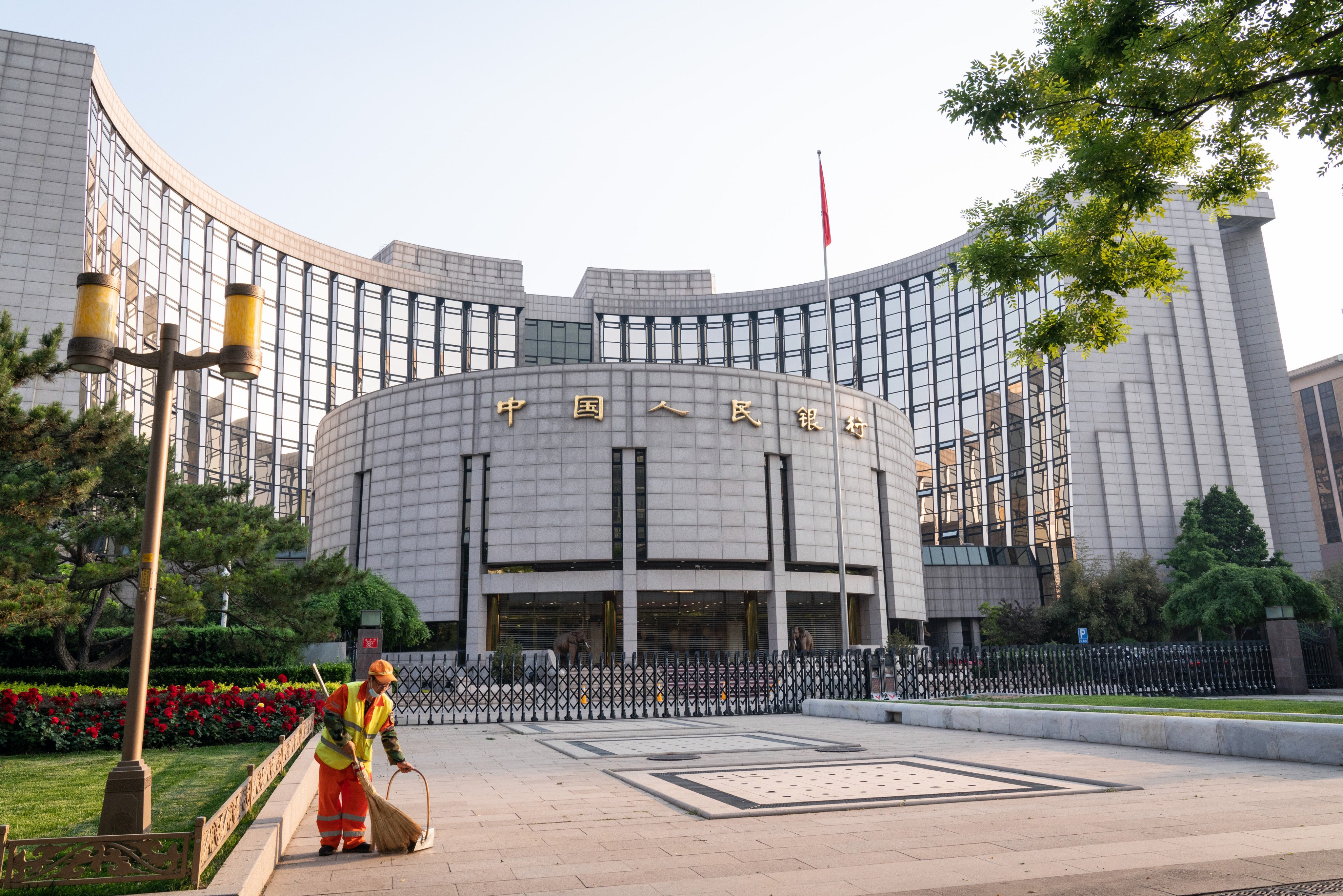 A cleaner sweeps the grounds in front of the People’s Bank of China headquarters in Beijing. Photo: Bloomberg