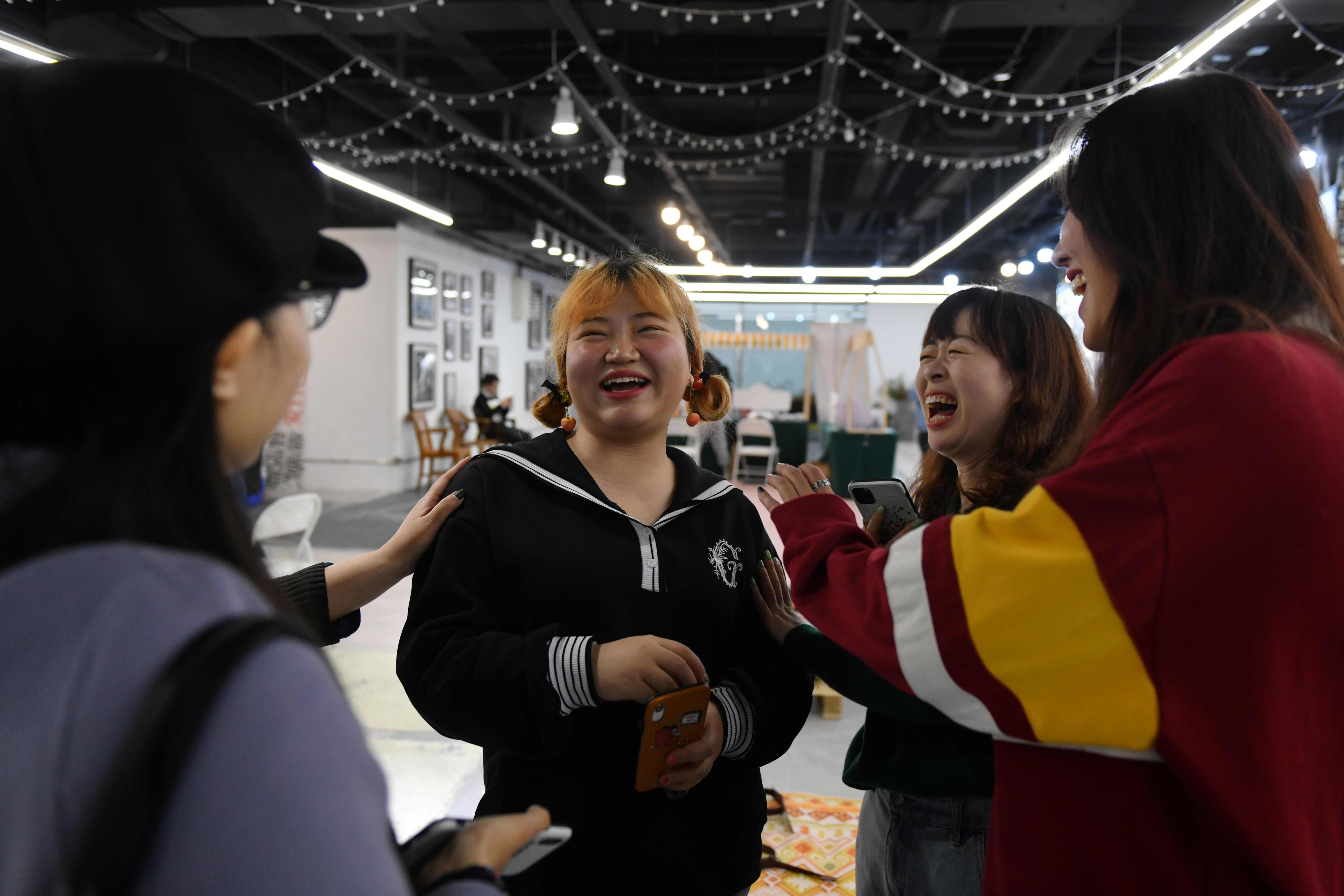 Stand-up comedian Qiqi (centre) chats with fellow comedians Ailun (right) and Yang Mei (second right) and fans after a performance at a shopping mall in Beijing in November 2020. Photo: AFP  
