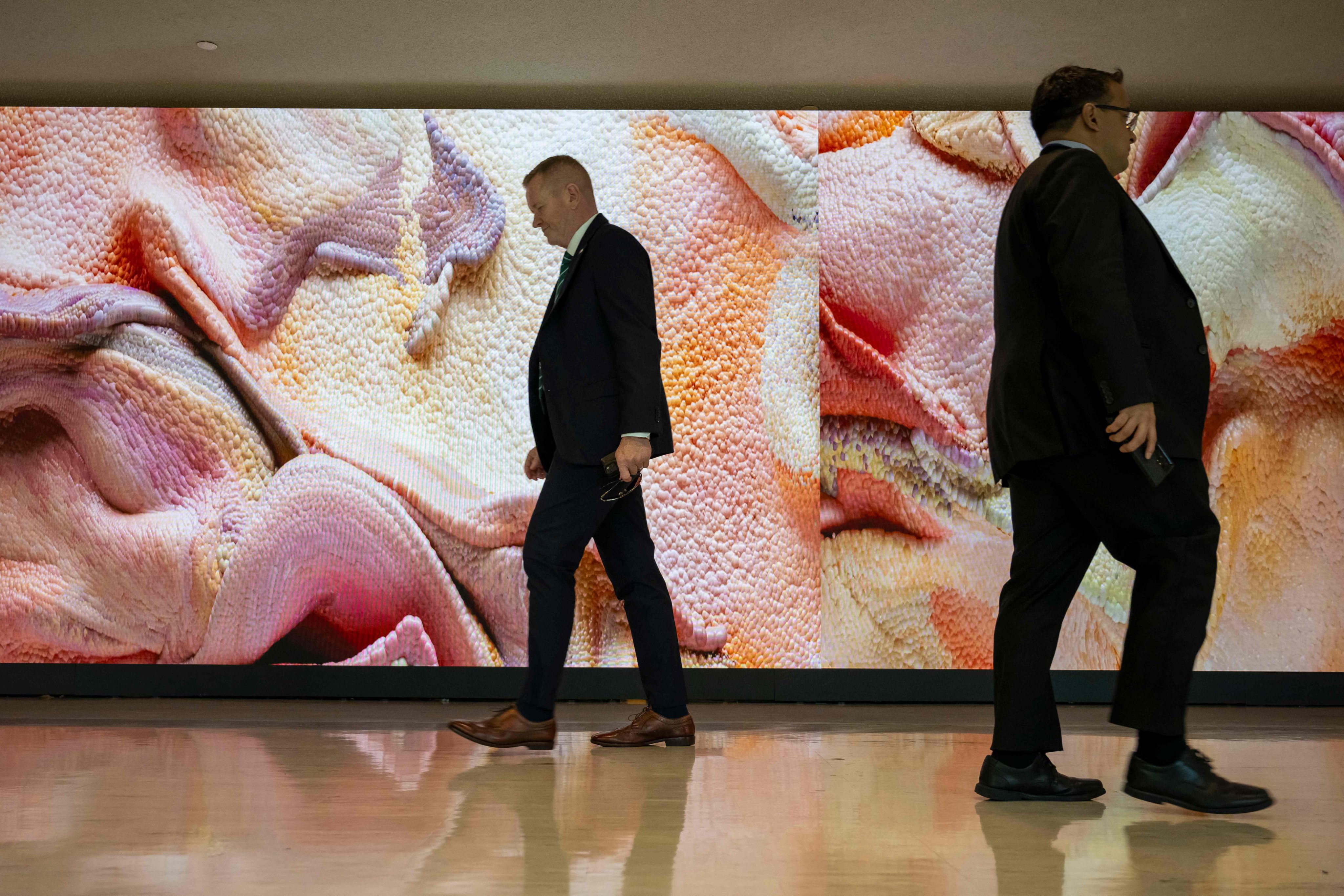 People walk past an AI-generated video art installation by artist Refik Anadol entitled ‘Large Nature Model: Coral’ to promote power of technology and sustainability at United Nations Headquarters on September 20, 2024 in New York City. (Photo by ANGELA WEISS / AFP) / RESTRICTED TO EDITORIAL USE - MANDATORY MENTION OF THE ARTIST UPON PUBLICATION - TO ILLUSTRATE THE EVENT AS SPECIFIED IN THE CAPTION