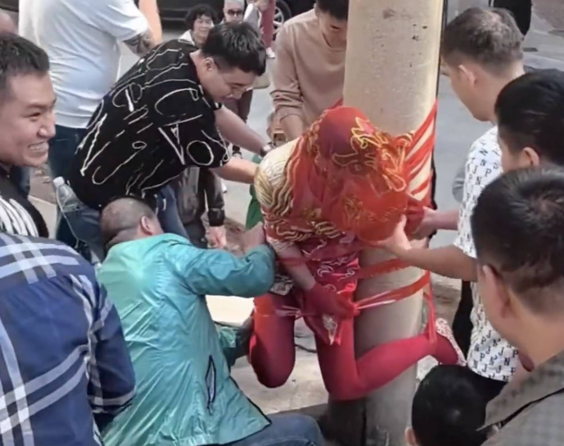 The bride, dressed in traditional wedding attire, is taped to a telephone pole. Photo: Weibo