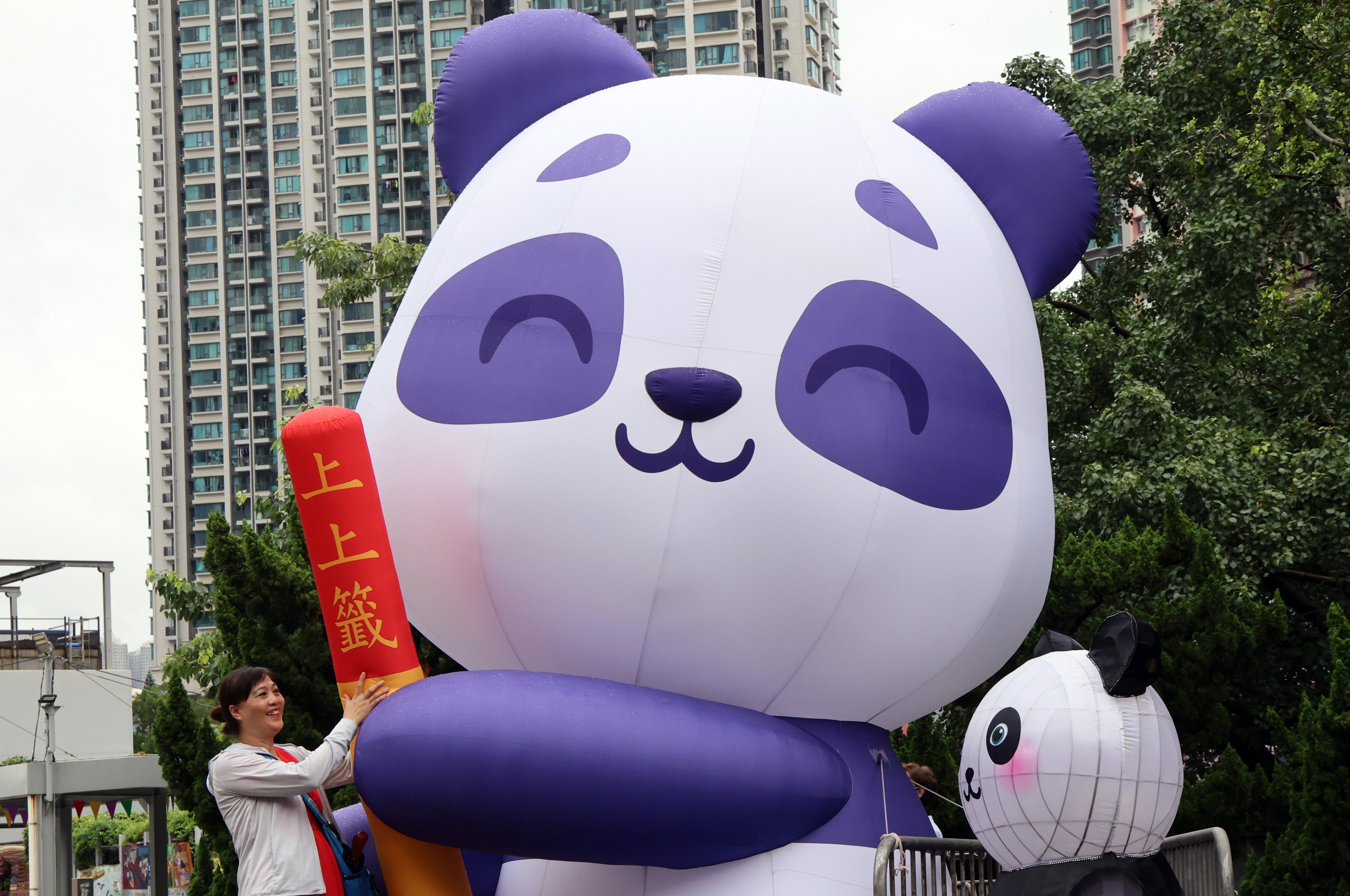 Hong Kong is in the throes of panda fever. A woman takes a photo with a blow-up panda doll in Wong Tai Sin Temple Square, ahead of the arrival of a pair of the bamboo-eating bears from Beijing. Photo: Jelly Tse