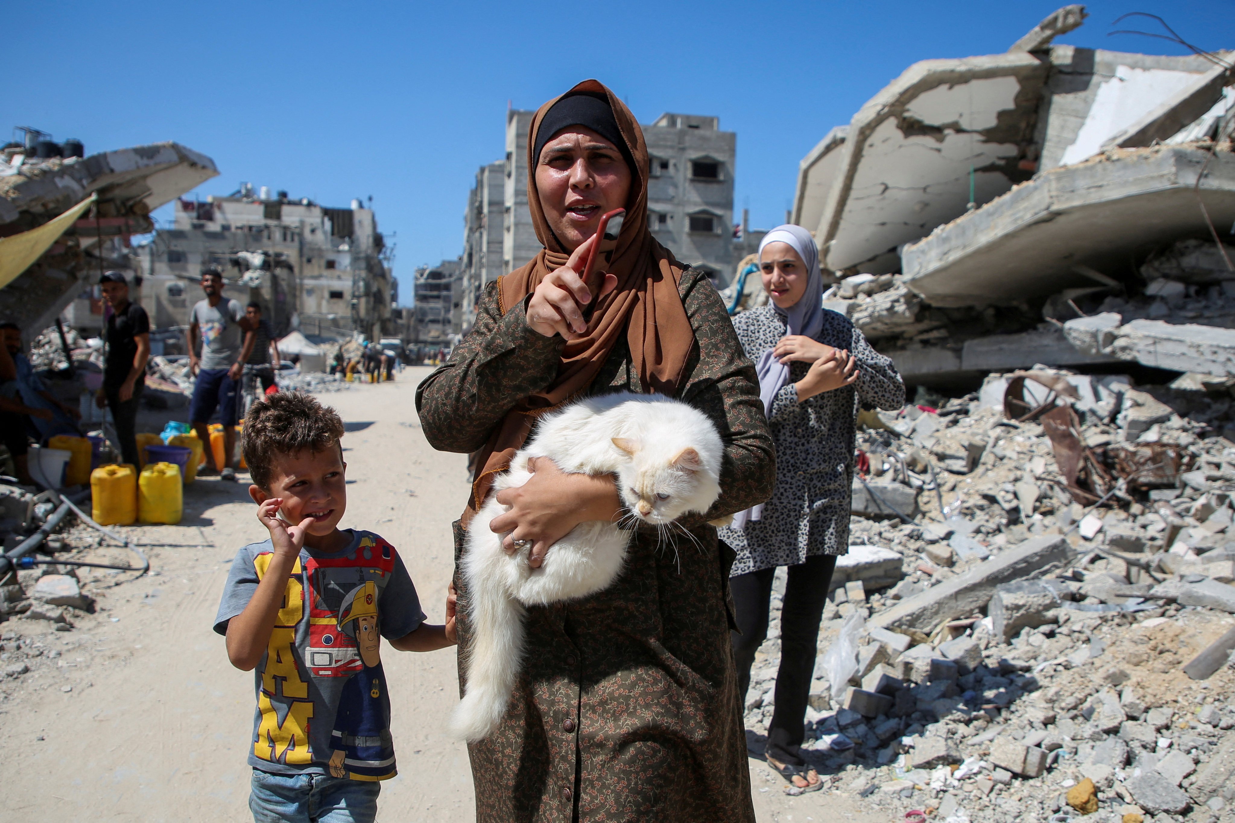 A Palestinian woman holds a cat as she walks pas the rubble of houses destroyed in the Israel’s military offensive in Khan Younis. Photo: Reuters