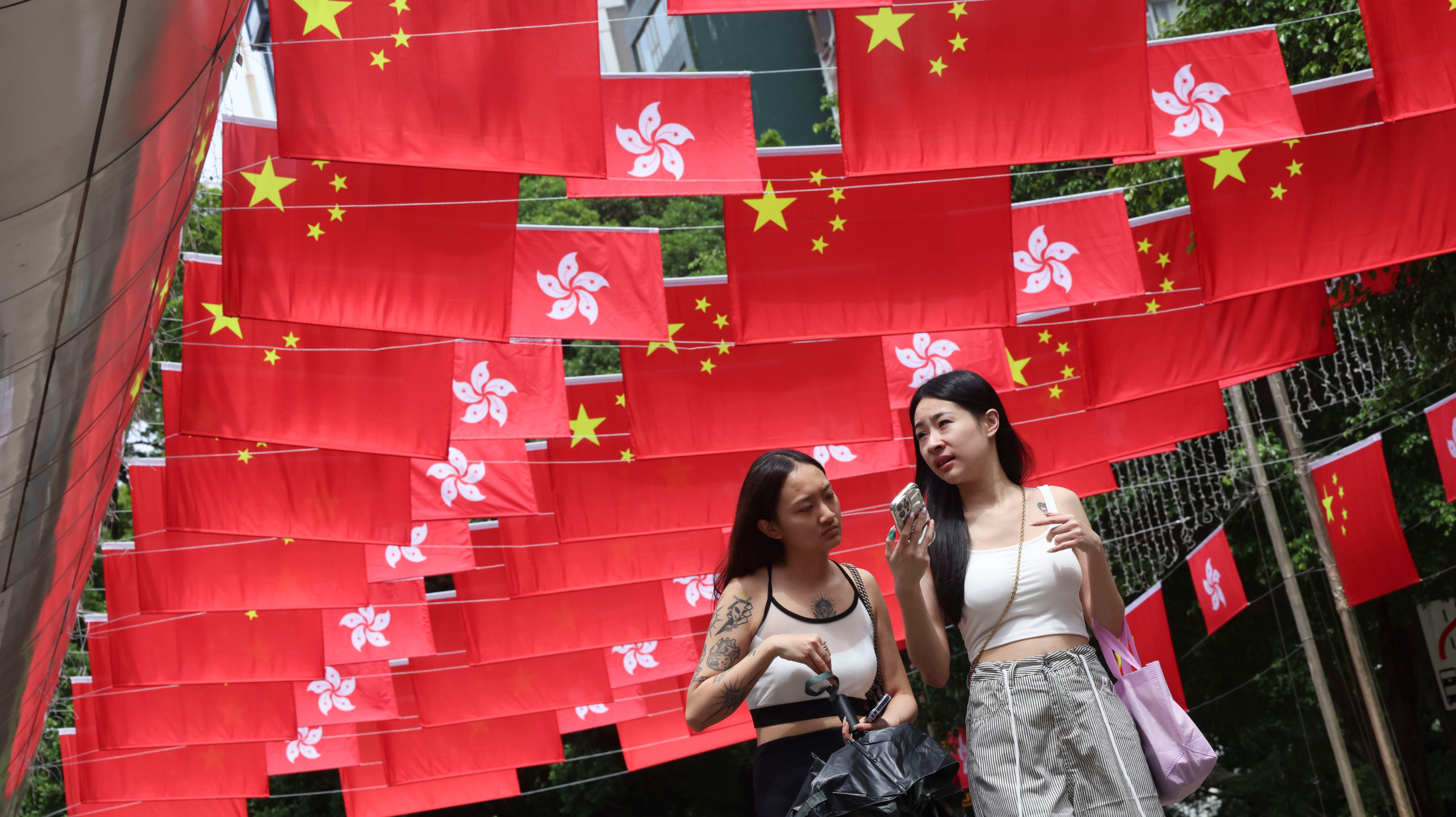 On September 25, 2024, tourists walk along Park Lane Shopper’s Boulevard in Tsim Sha Tsui, which is festooned with flags to celebrate the 75th anniversary of the founding of the People’s Republic of China. Photo: Jelly Tse