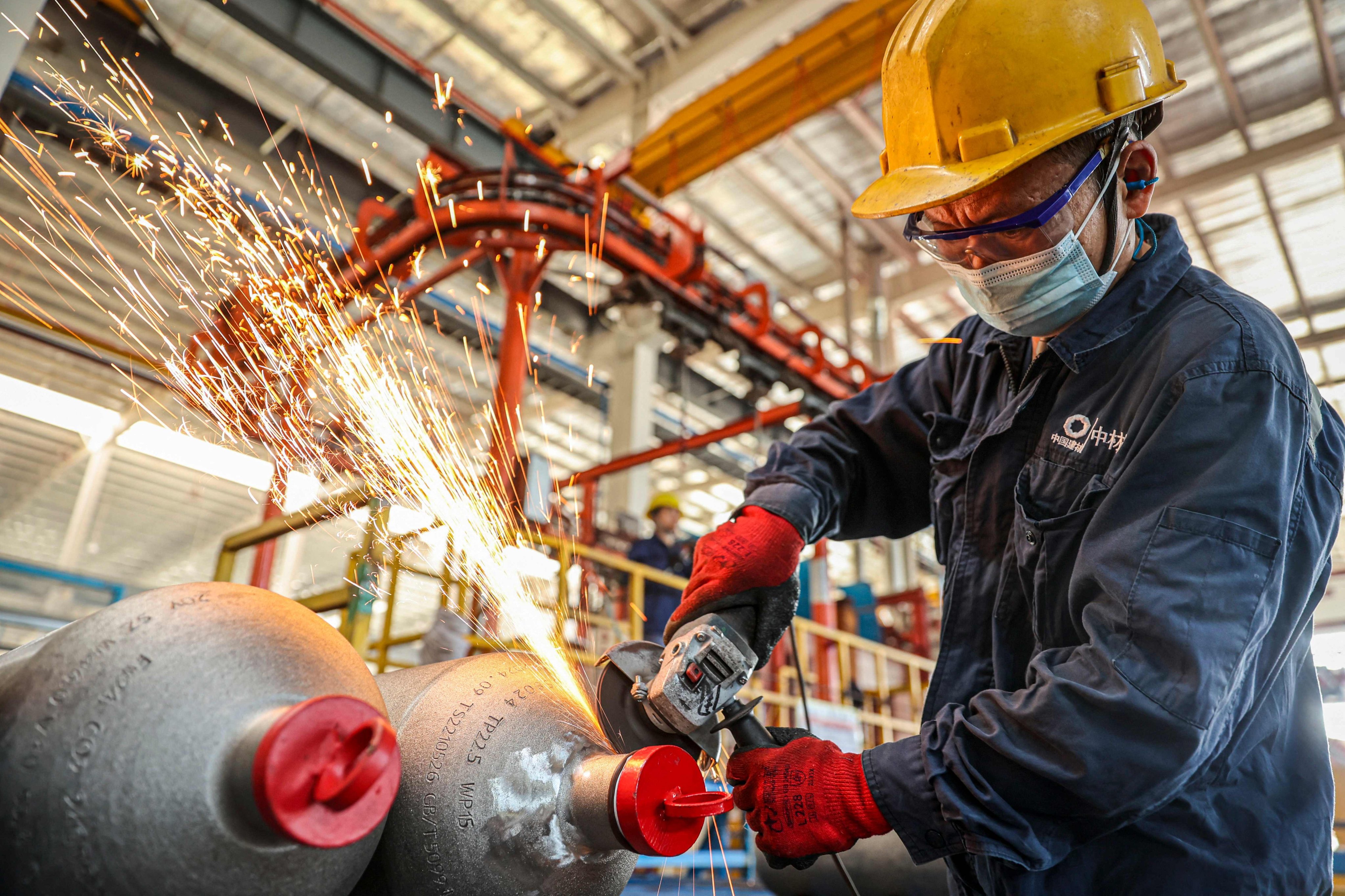 A worker polishes newly-produced gas cylinders at a factory in Ruichang, in central China’s Jiangxi province. Photo: AFP