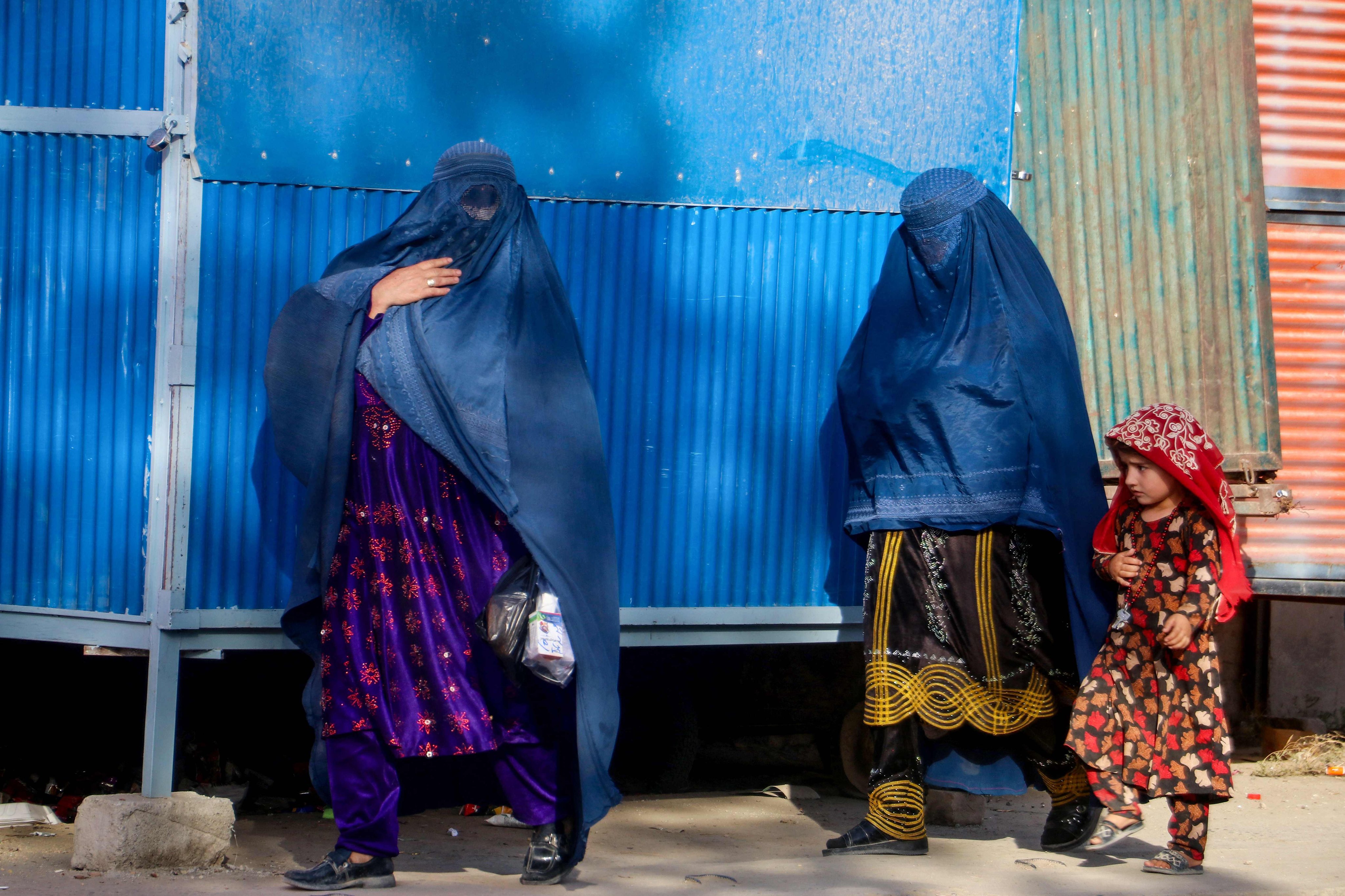 Burqa-clad women walk with a girl along a street in Fayzabad district, Badakhshan province in Afghanistan on September 22. Photo: AFP