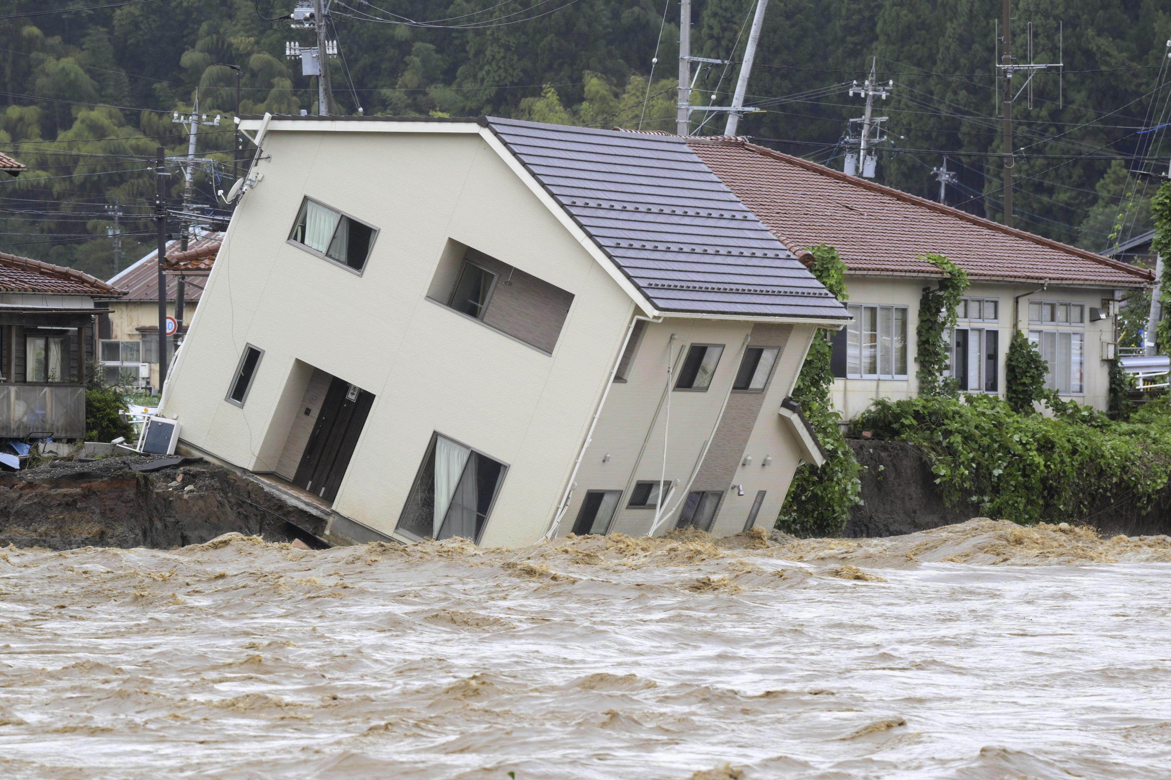 A house in central Japan’s Noto peninsula risks being washed away by a swollen river following last month’s heavy rain. Photo: Kyodo News via AP