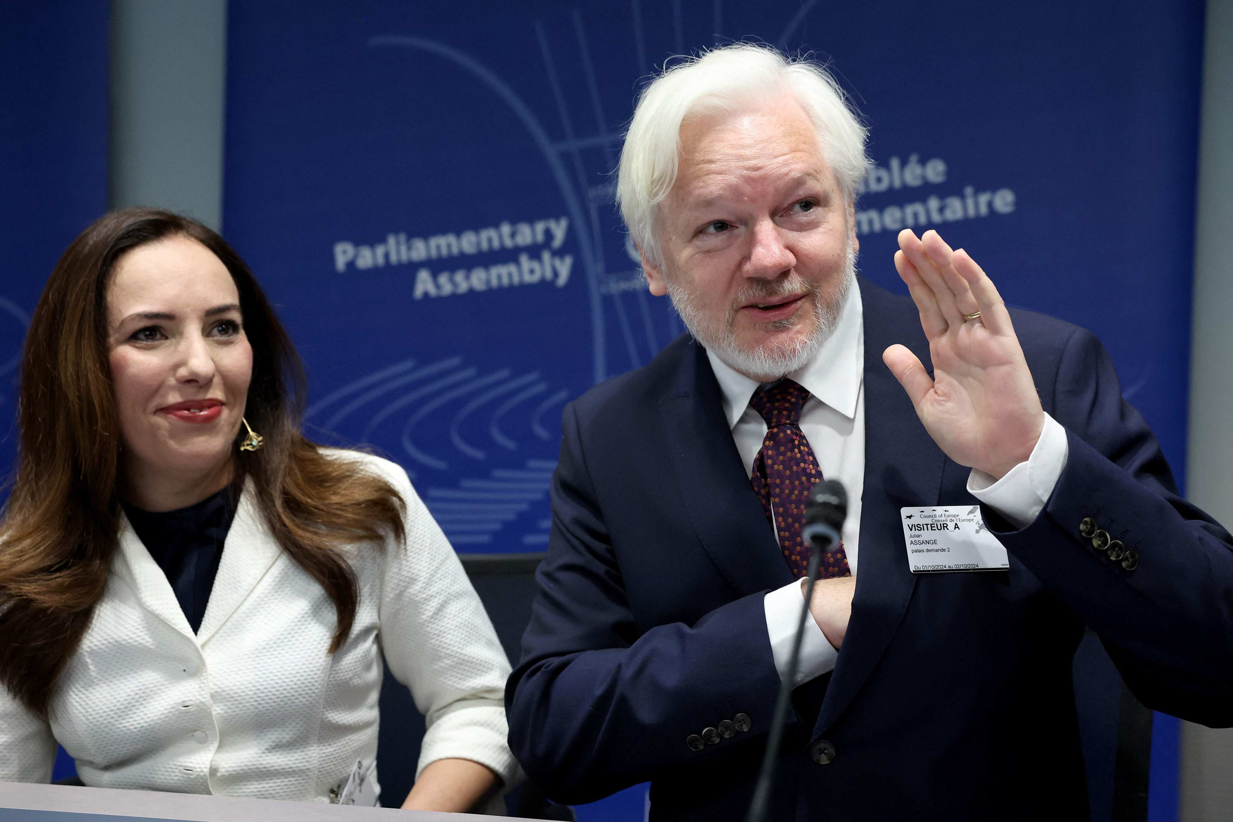 Dressed in a black suit with a burgundy tie and wearing a slight white beard, Julian Assange sat between his wife Stella. Photo: AFP