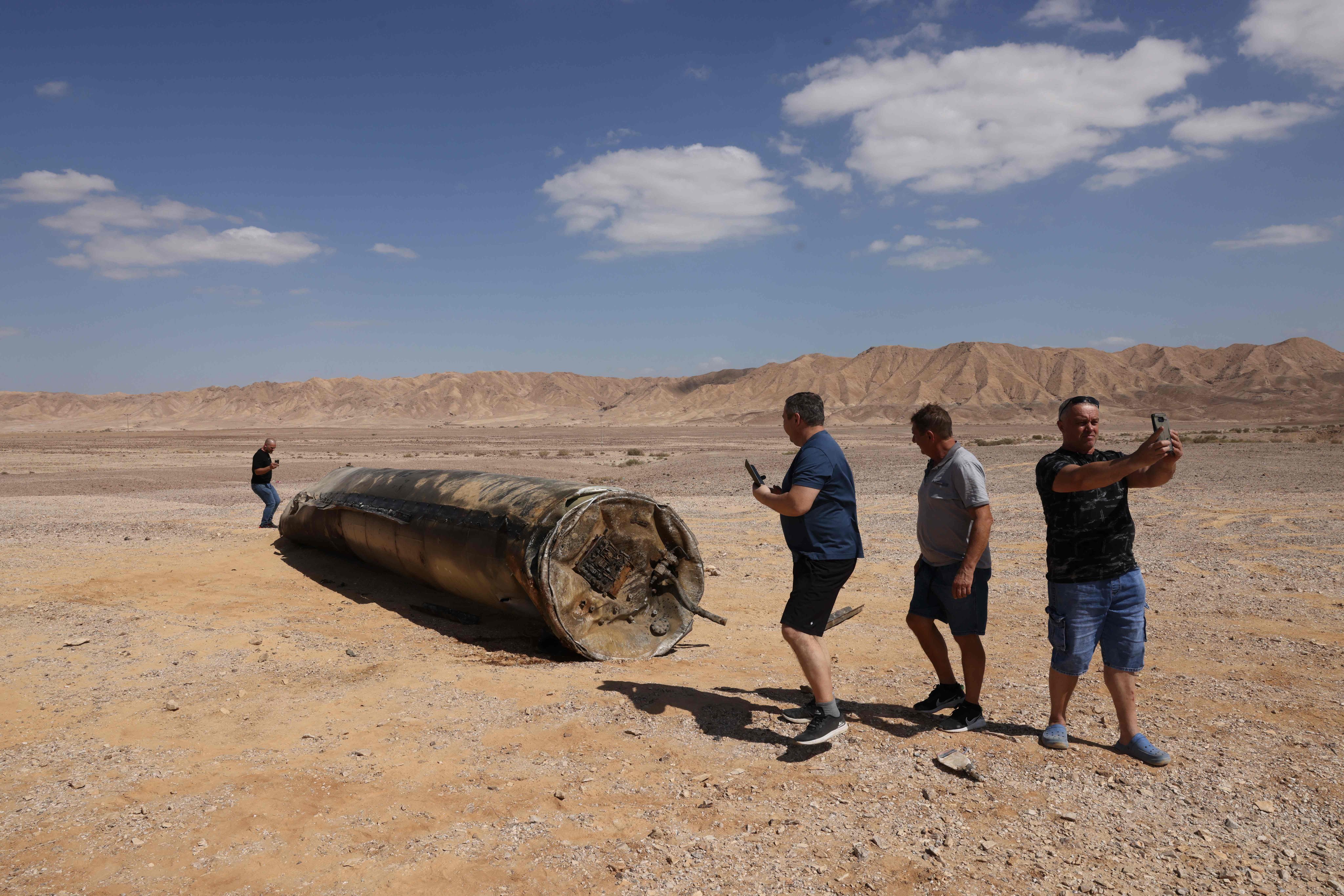 People take pictures near the remains of an Iranian missile in the Negev desert near Arad, Israel. Photo: AFP