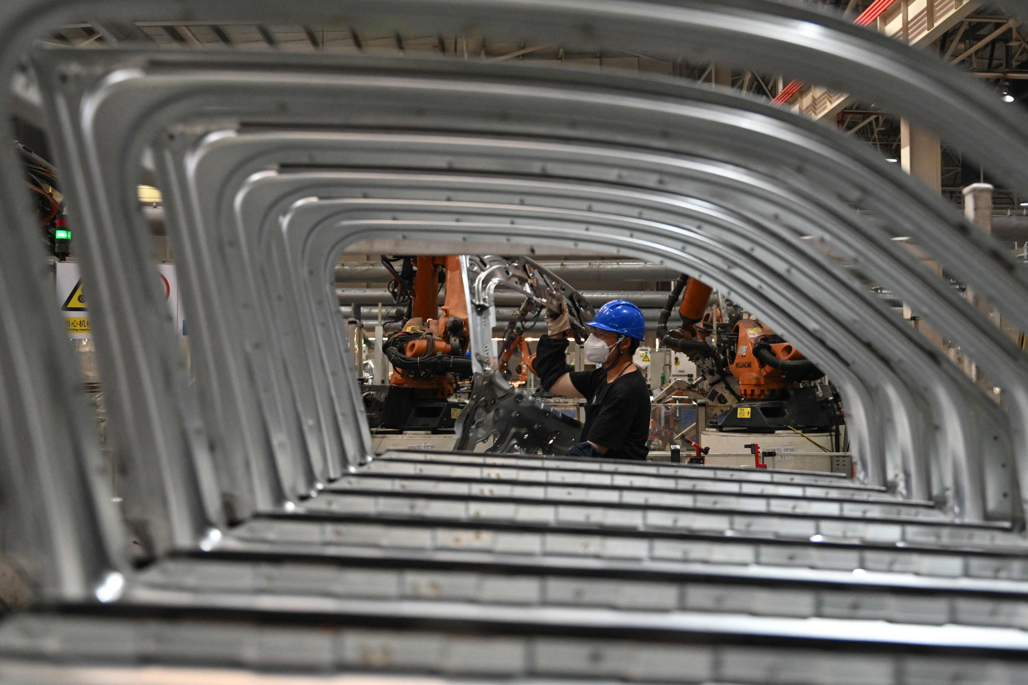 An employee carries a door frame on an electric vehicle production line at the Leapmotor factory in Jinhua, in Zhejiang province, on September 18. Photo: AFP