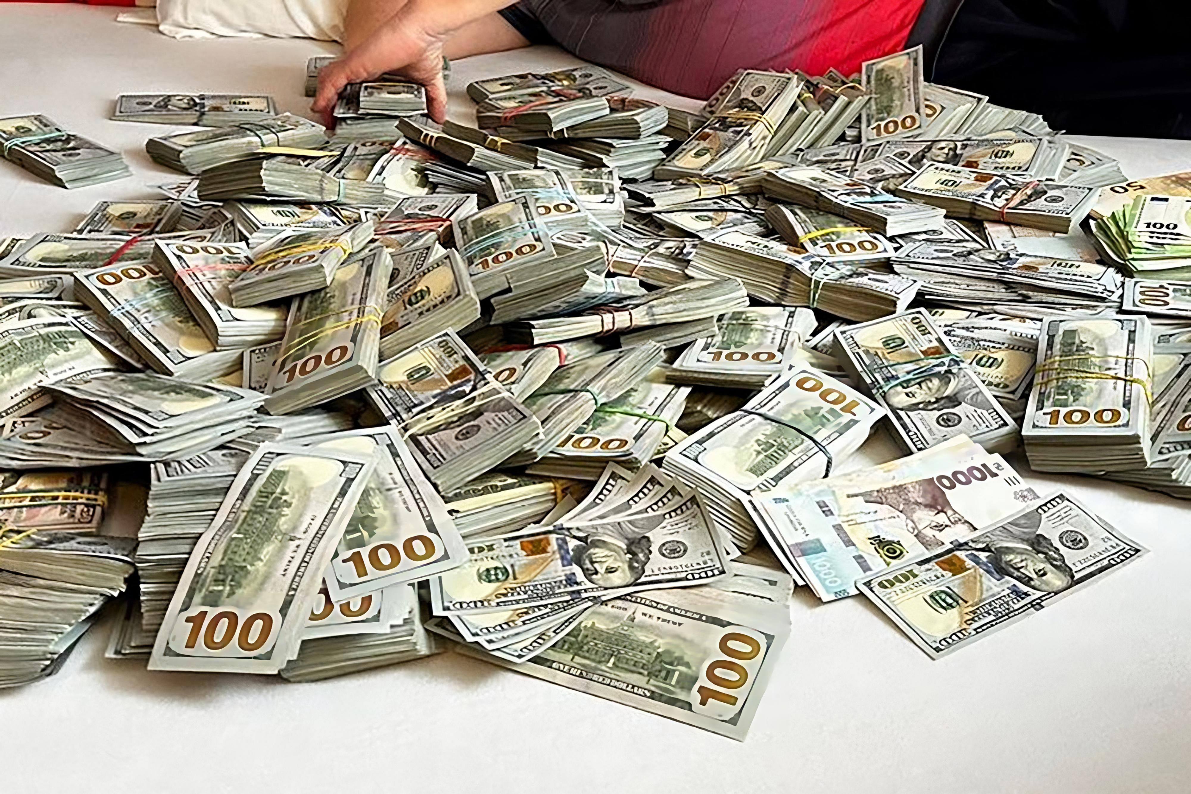 Wads of US dollar notes spread out on a bed at an official’s home during a raid in Ukraine’s Khmelnitsky region. Photo: SBI/AFP