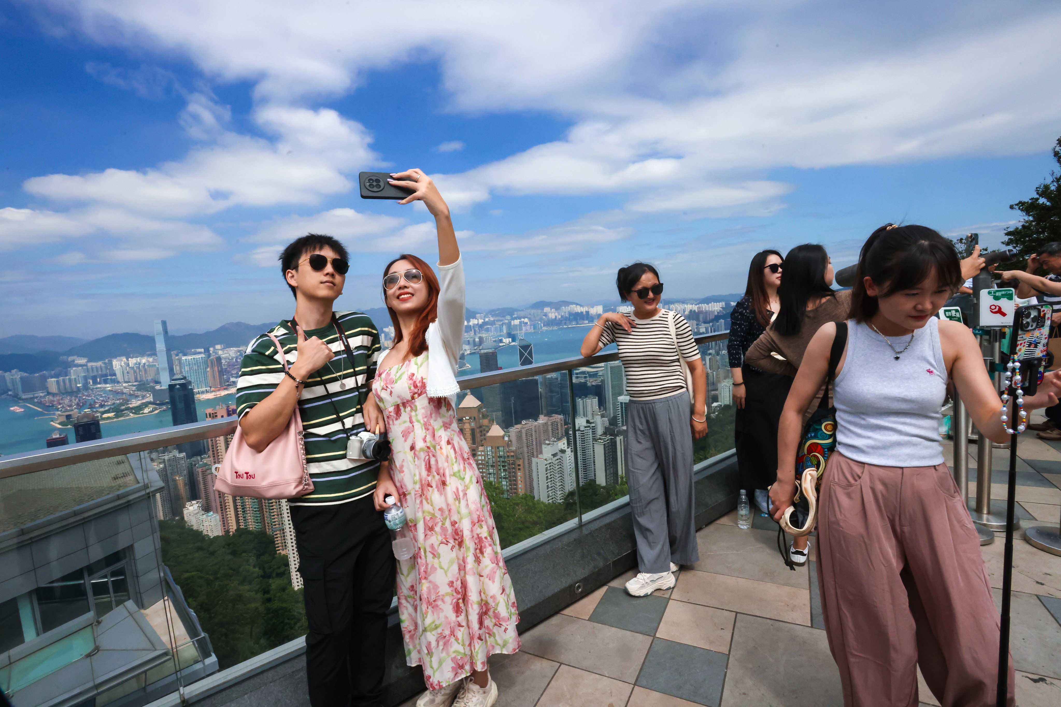 Visitors pose for photos against the backdrop of Hong Kong’s iconic skyline. Photo: Jonathan Wong