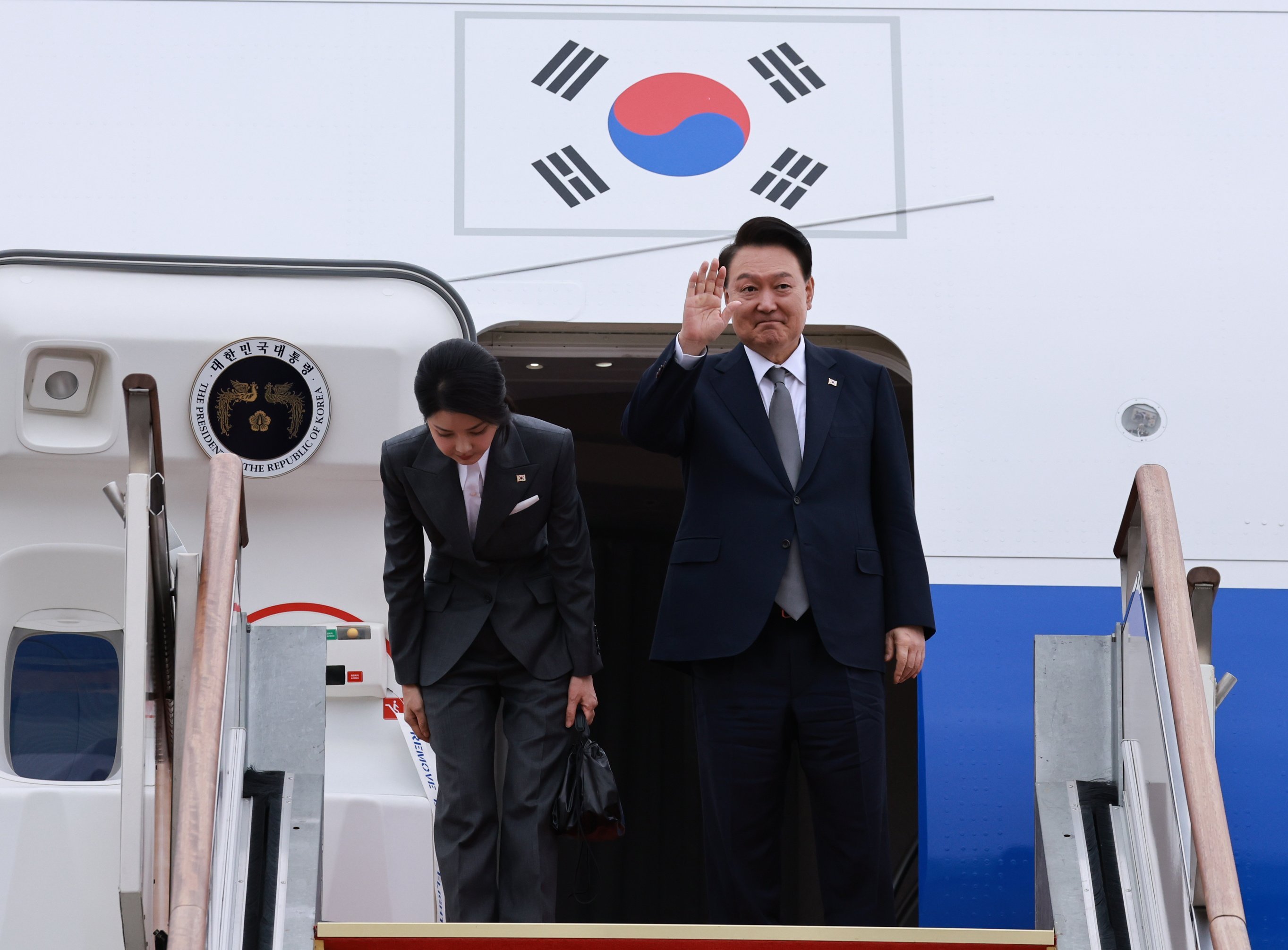 South Korean President Yoon Suk-yeol waves as first lady Kim Keon-hee bows next to him before their departure to the Philippines on the first leg of a three-nation tour.  Photo: EPA-EFE/Yonhap