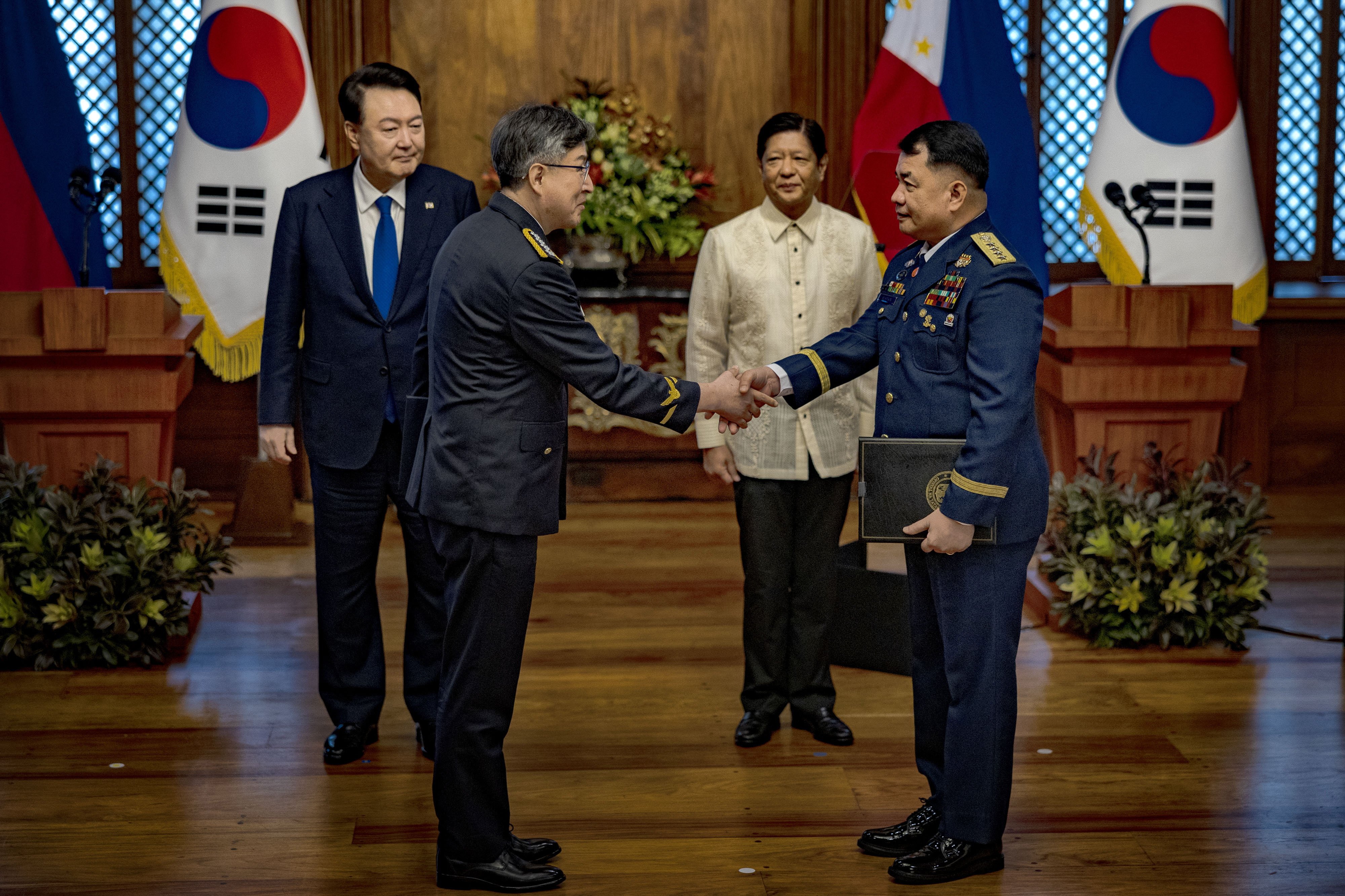 South Korea’s Yoon Suk-yeol and Philippine President Ferdinand Marcos Jnr look on as their countries’ coastguard chiefs shake hands in Manila on Monday. Photo: EPA-EFE