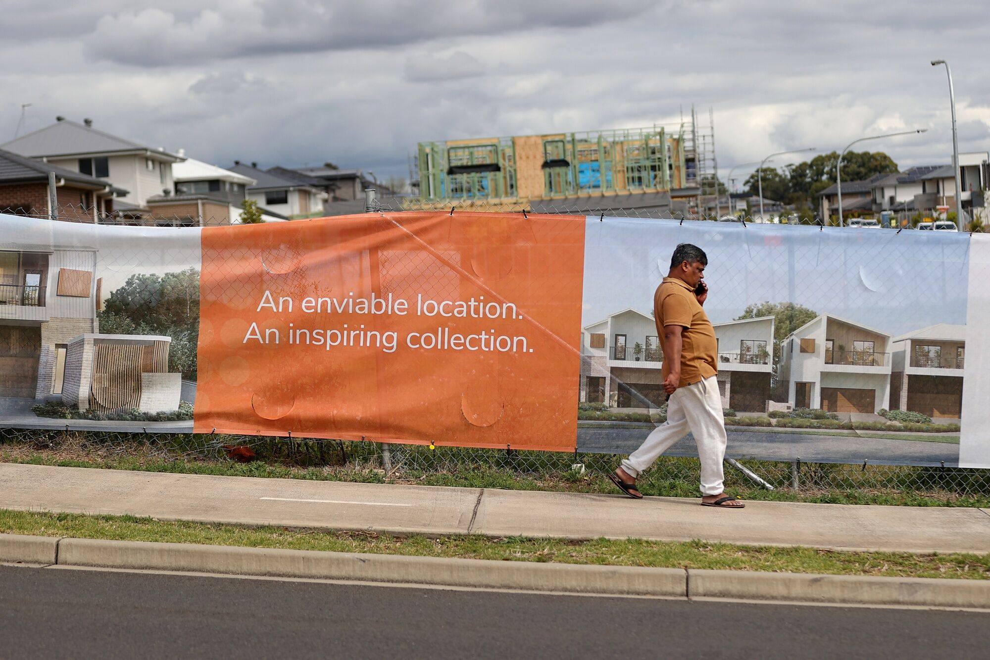 A banner displays a picture of new houses with construction in the background in the Caddens suburb of Sydney, Australia, on September 28. While Australia is not the only major Asian economy facing a housing crisis, it is among the most severe. Photo: Bloomberg