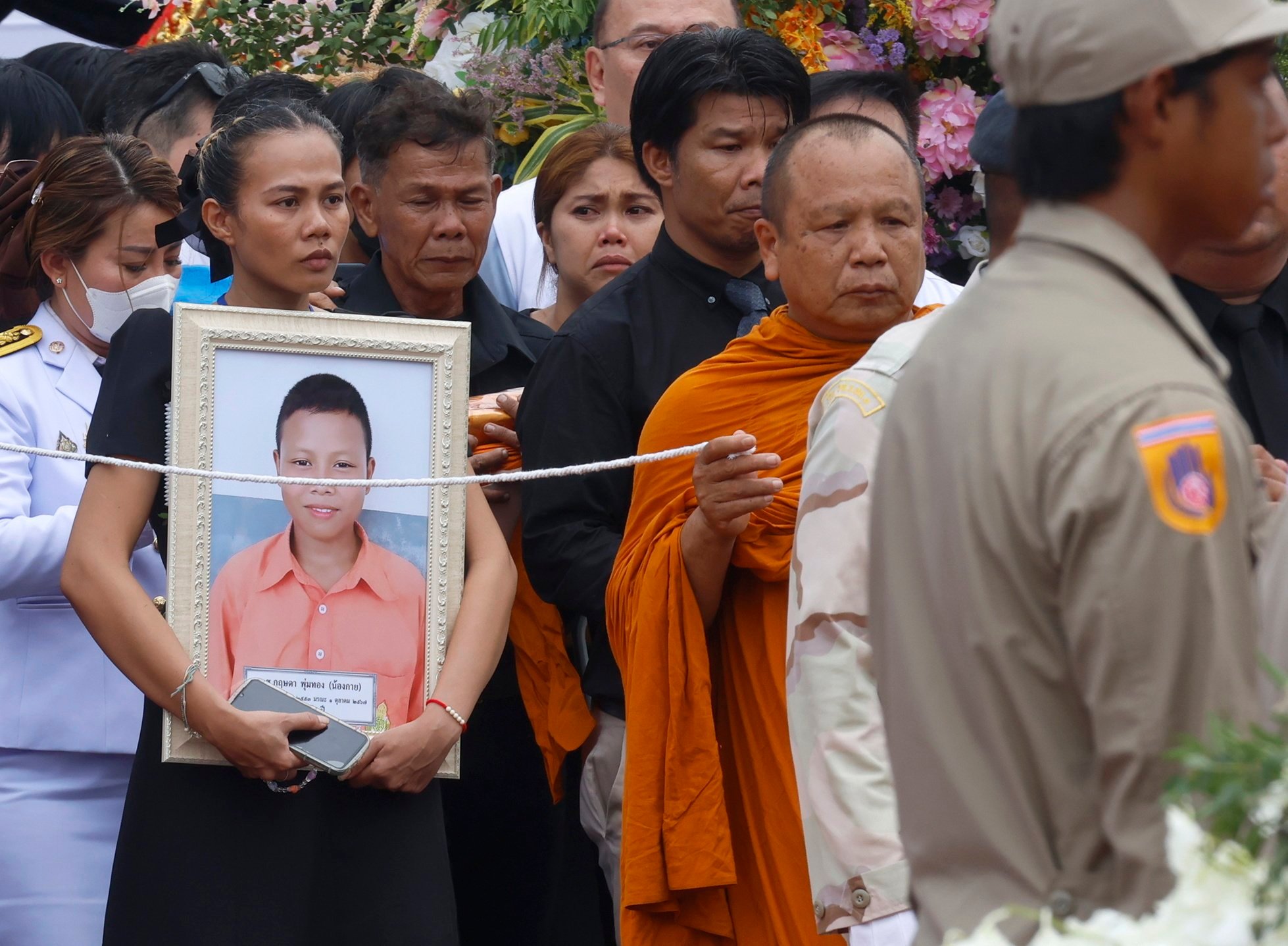 A mother mourns as she carries her son’s picture during the royal sponsored mass cremation rite for the victims of a Thai bus fire, at Uthai Thani province, Thailand on Tuesday. Photo:  EPA-EFE