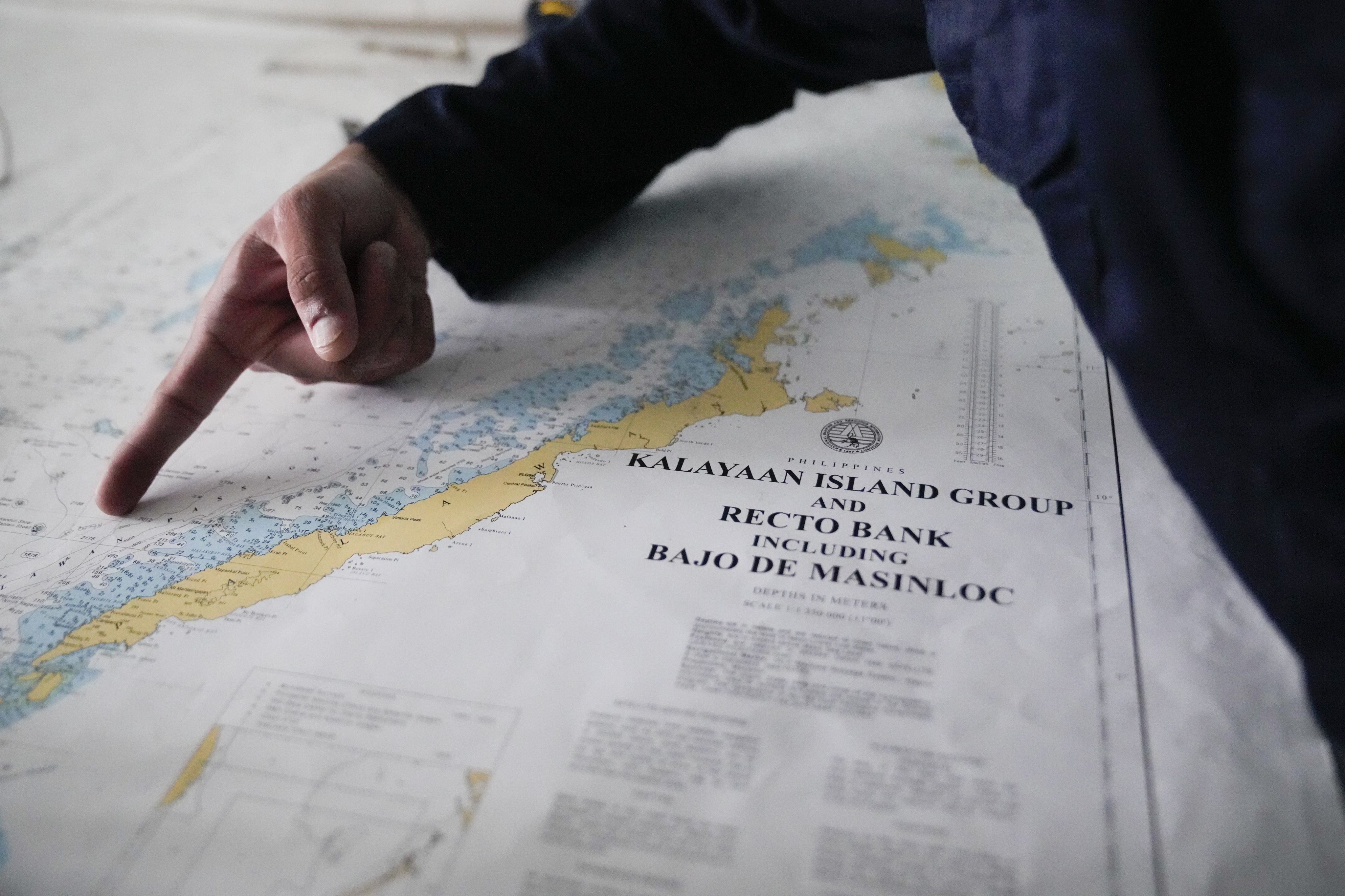 A member of the Philippine coastguard points at a map showing Palawan province and other Philippine-occupied areas in the South China Sea last year. Photo: AP