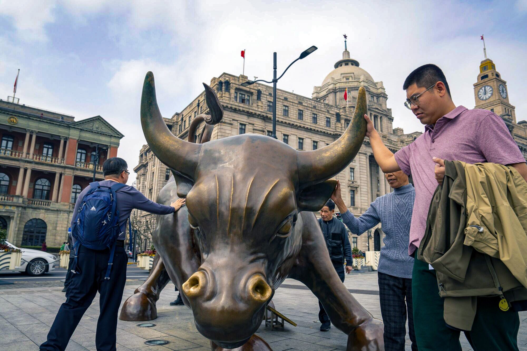 Pedestrians touch the Bund Bull in Shanghai. Chinese stocks jumped as onshore traders returned from the “golden week” holiday, but later pared gains on lack of further stimulus. Photo: Bloomberg