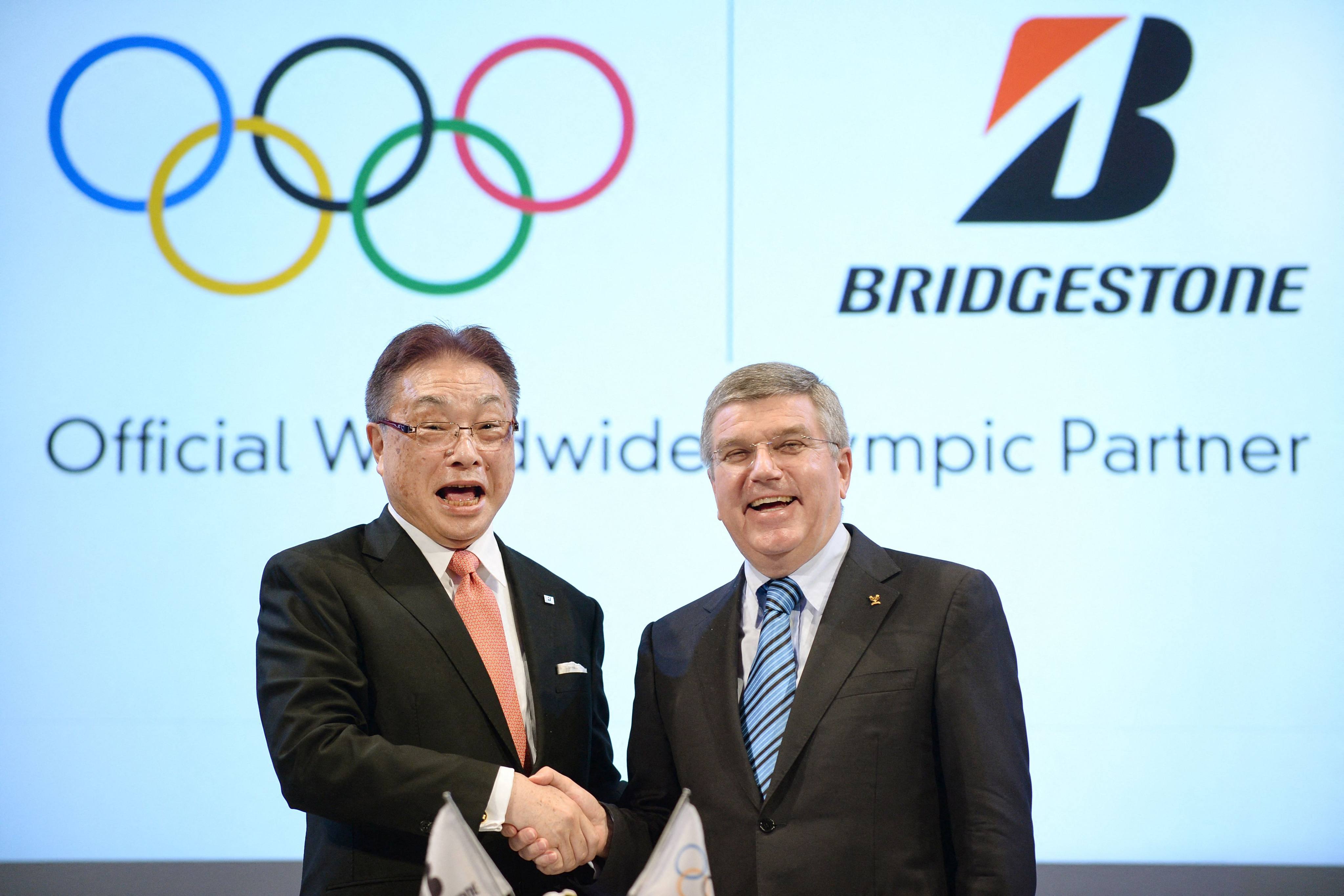 IOC President Thomas Bach (right) shakes hands with chairman and CEO of Japan’s tyre maker Bridgestone, Masaaki Tsuya in 2014, when Bridgestone became an official Olympic sponsor. Photo: AFP