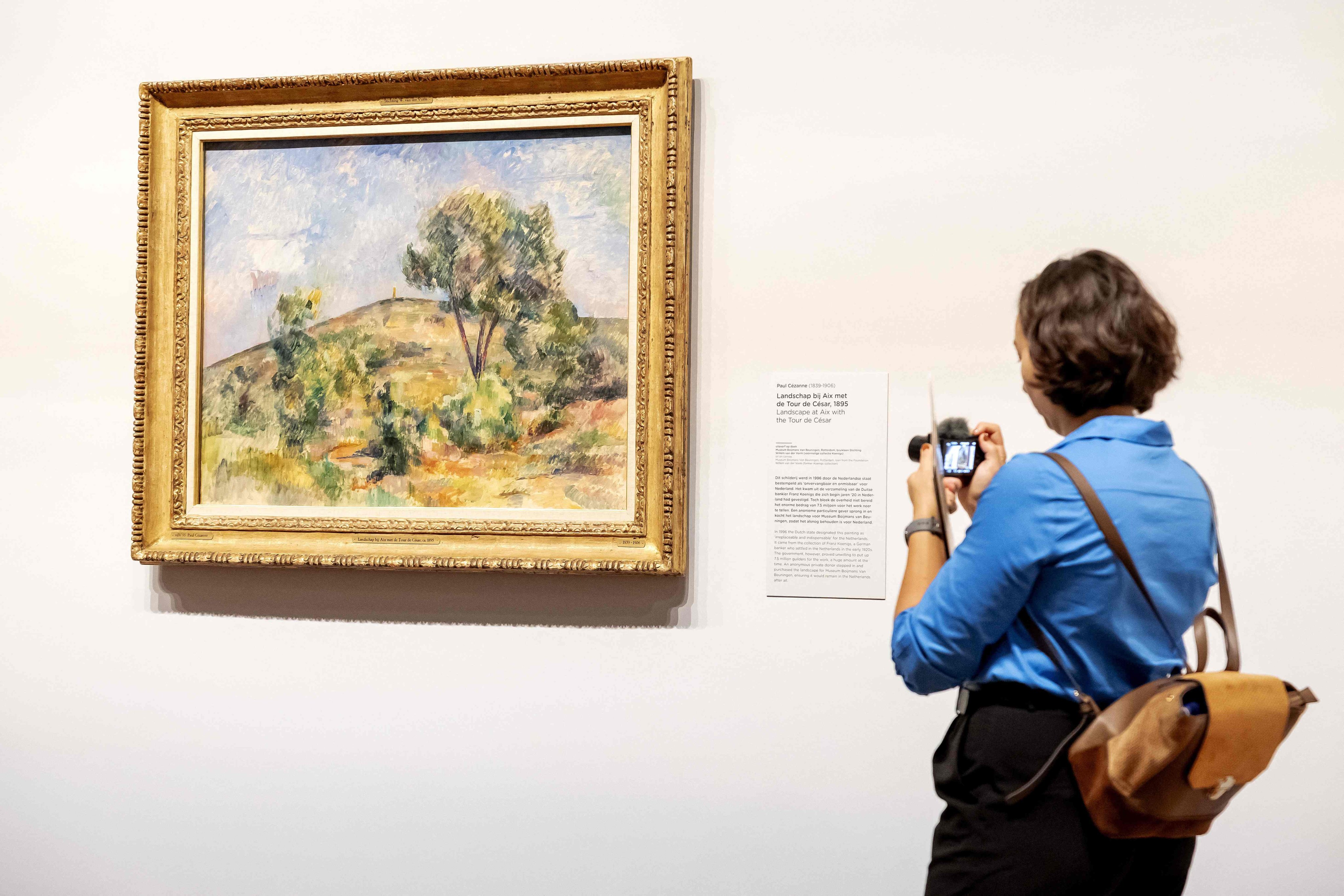 A woman looks atLandscape near Aix with Tour de Cesar by Paul Cézanne at the Van Gogh Museum in Amsterdam. Photo: AFP