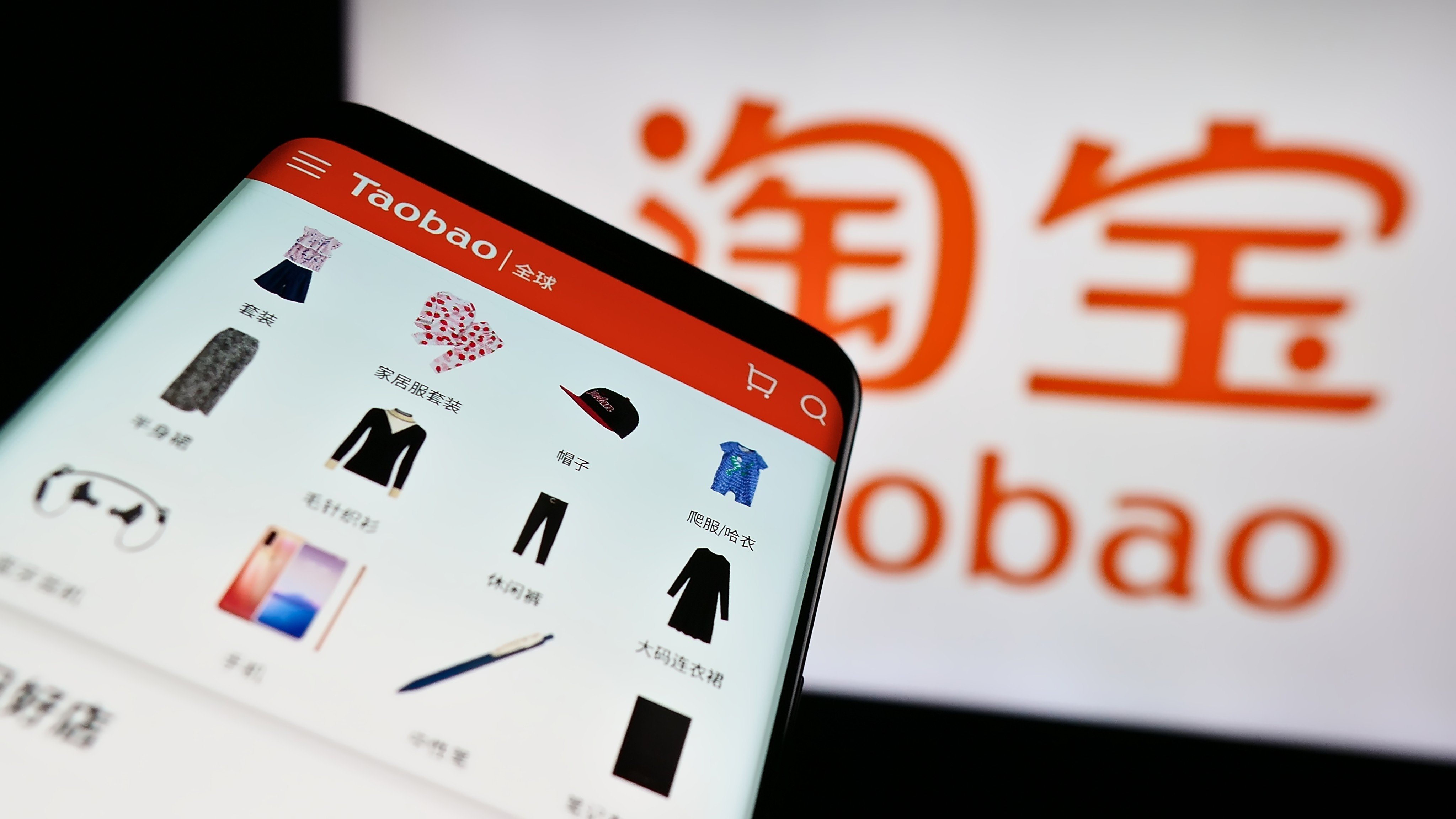 A mobile phone shows the Taobao website with its logo behind. Photo: Shutterstock Images