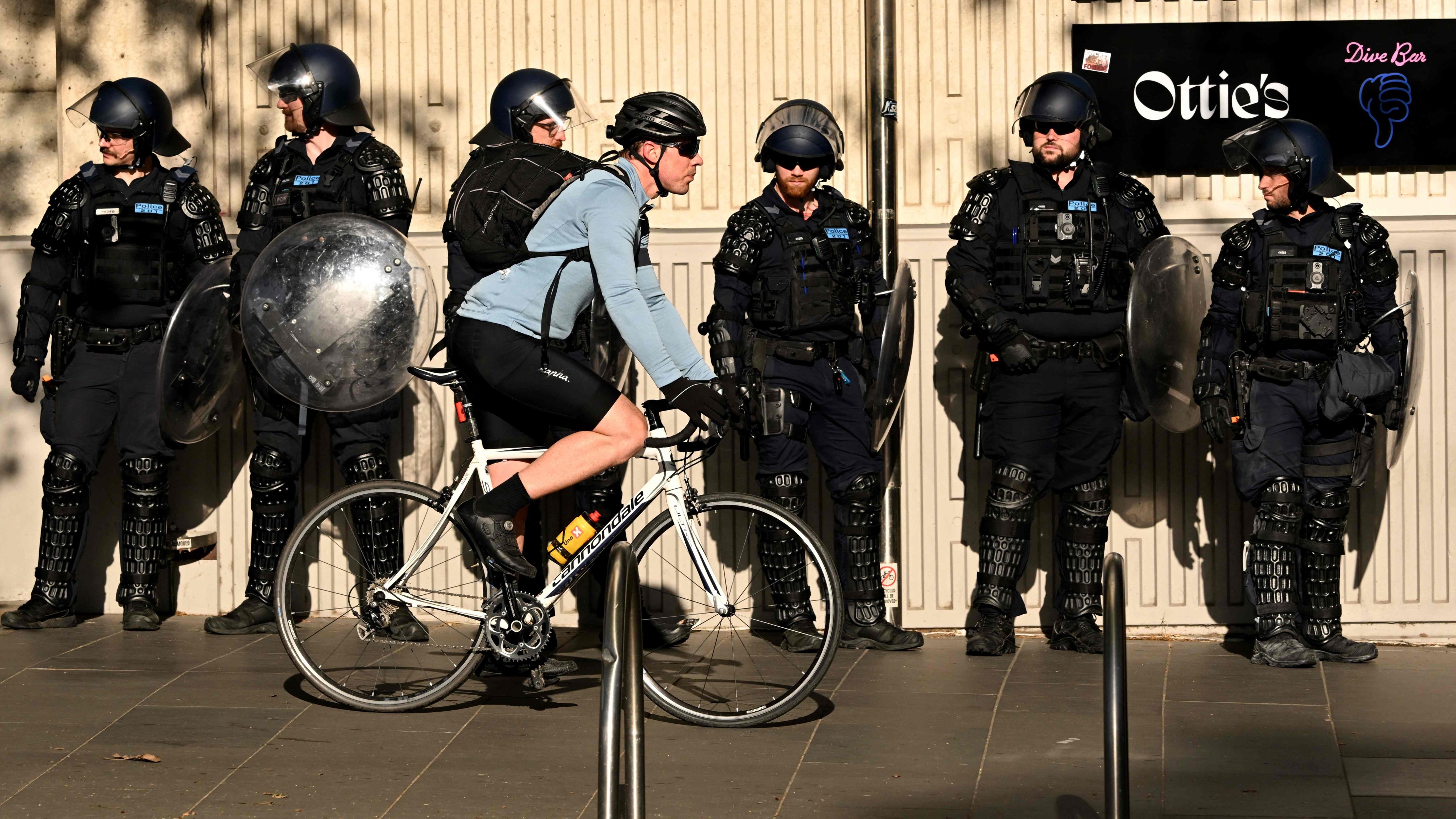 File Photo: A cyclist passes riot police outside the Land Forces 2024 arms fair in Melbourne on September 12. Photo: AFP