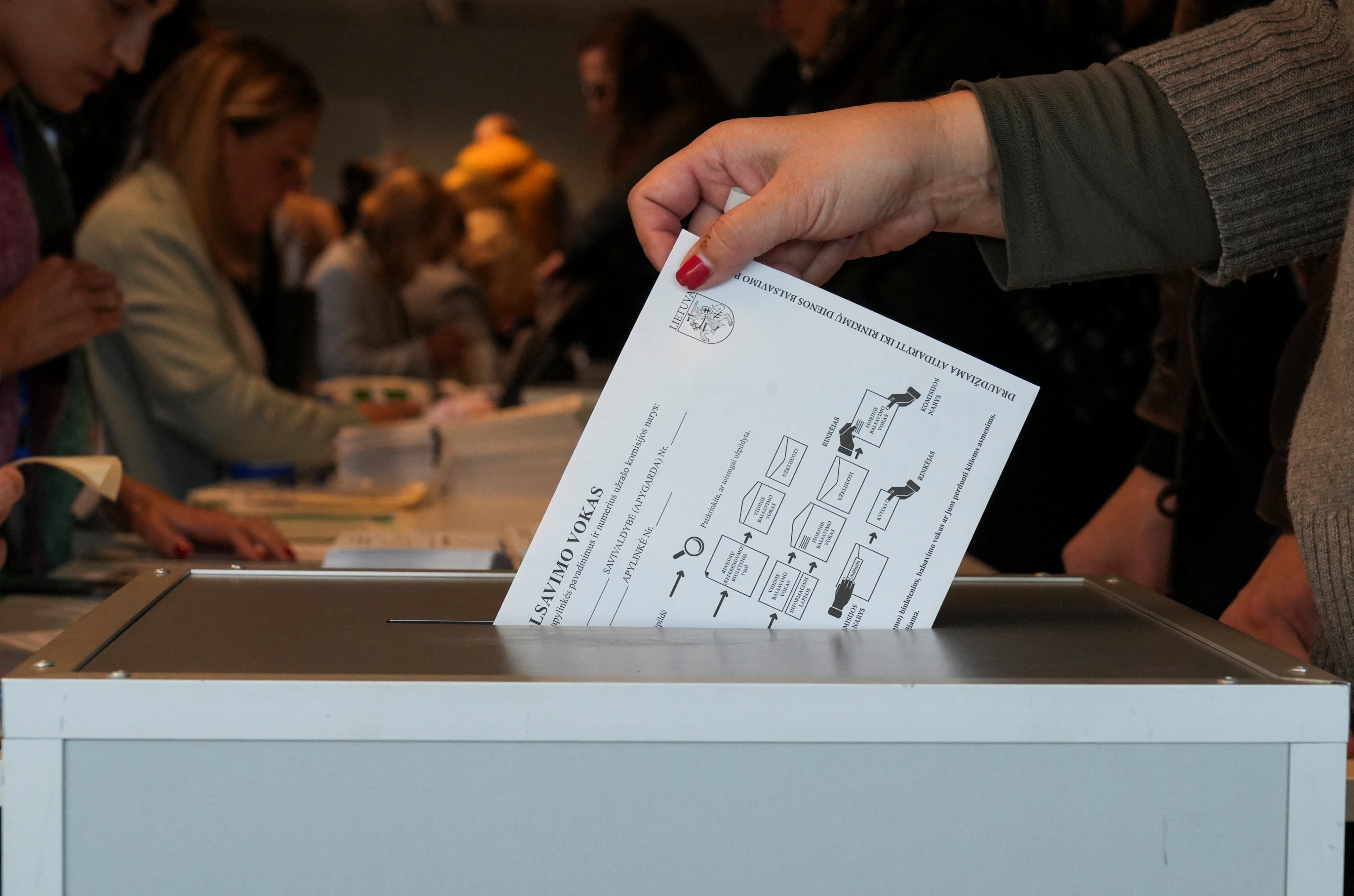 A voter casts a ballot into the box during early voting in the Lithuanian general elections, in Vilnius, Lithuania. Photo: Reuters