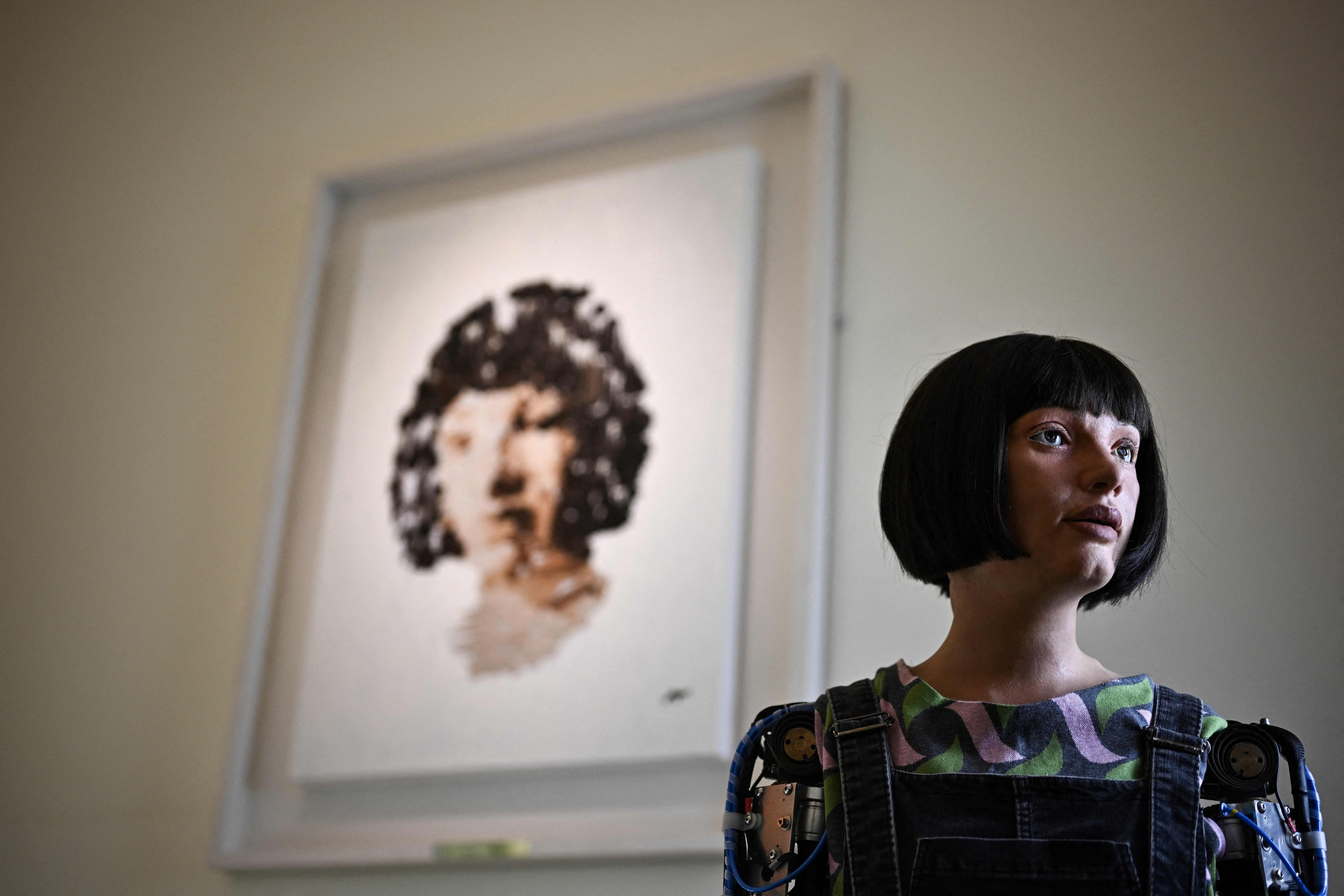 Ai-Da poses in front of a painting she made during the press preview of the London Design Biennale 2023 at Somerset House, central London, in June 2023. Photo: AFP